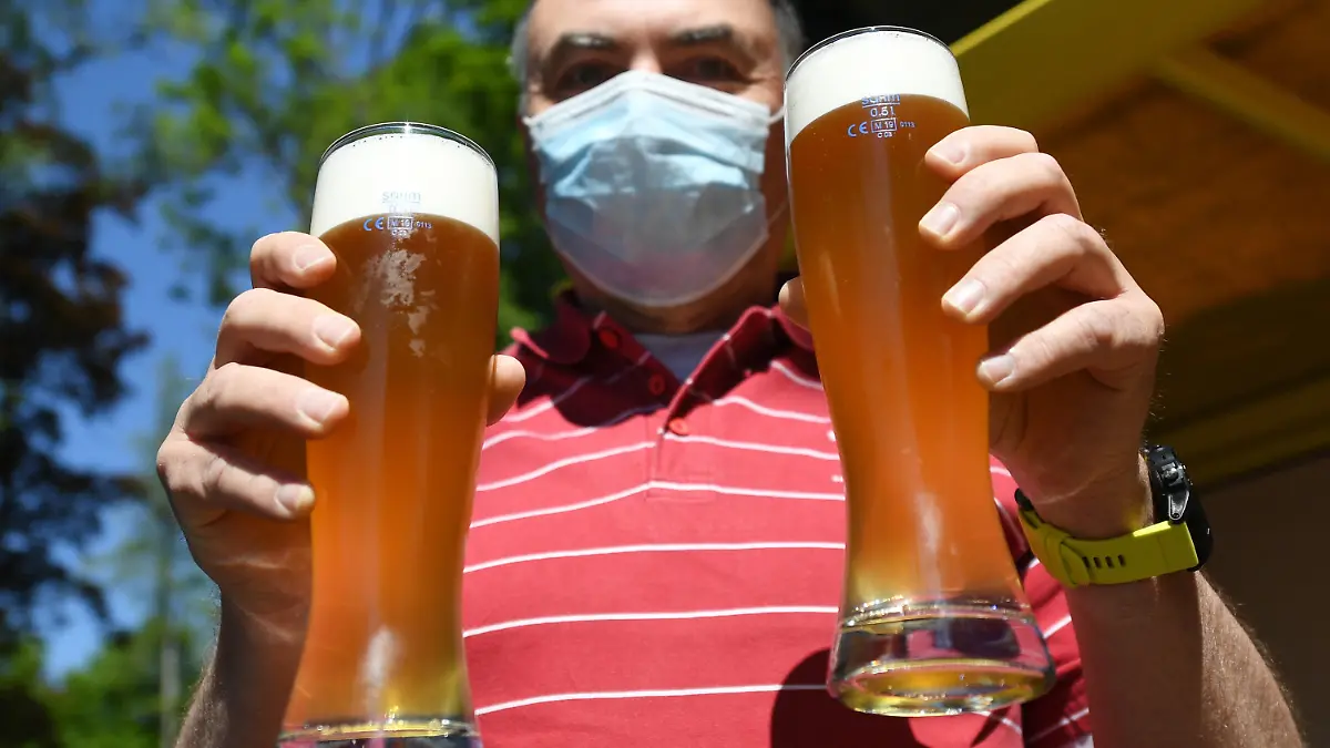 18.05.2020, Bayern, Uffing: Ein Mann hält seine eben gekauften Biergläser in einem Biergarten am Staffelsee hoch. Ab dem 18. Mai darf die Gastronomie in Bayern nach der Coronapause wieder die Außenbereiche und Biergärten bis 20 Uhr öffnen. Es gelten strenge Hygiene- und Abstandsregeln. Foto: Angelika Warmuth/dpa +++ dpa-Bildfunk +++