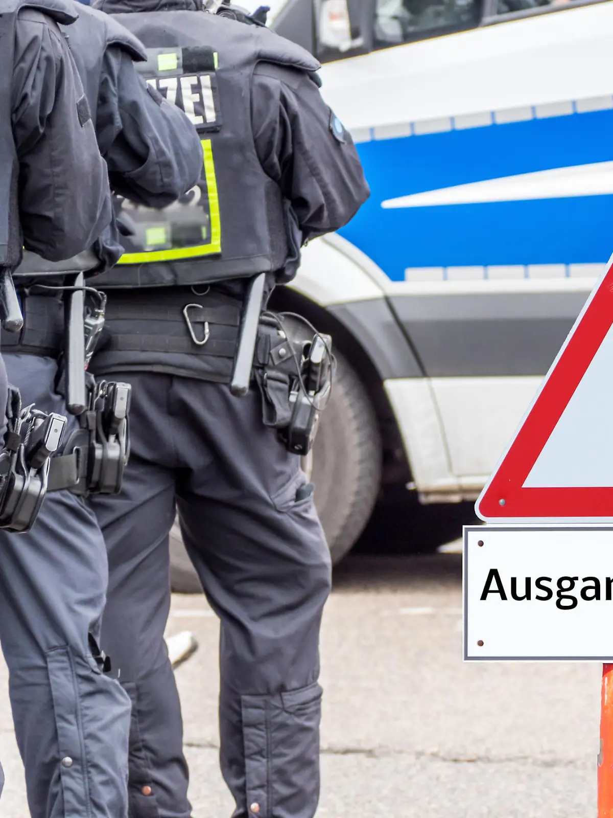 Polizei neben Warnschild, auf dem "Ausgangssperre" steht