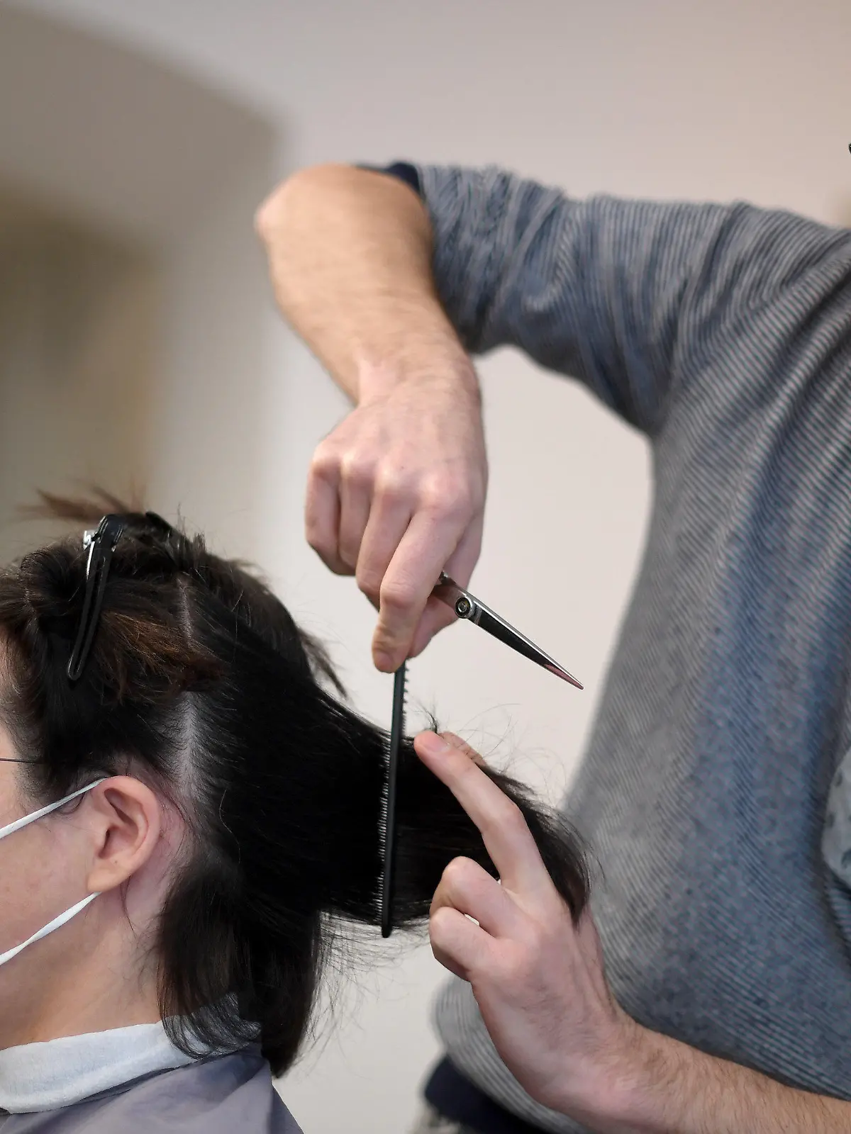 08.02.2021, Österreich, Wien: Ein Friseur schneidet einer Kundin in seinem Salon die Haare; beide tragen FFP2-Masken. Nach sechs Wochen Lockdown aufgrund der Corona-Pandemie öffnen in Österreich ab 08.02.2021 die Geschäfte wieder. Für körpernahe Dienstleistungen - wie zum Beispiel einen Friseur-Besuch - ist ein negativer Corona-Test nötig. Das Tragen einer besonders schützenden FFP2-Maske wird nahezu überall Pflicht. Foto: Roland Schlager/APA/dpa +++ dpa-Bildfunk +++