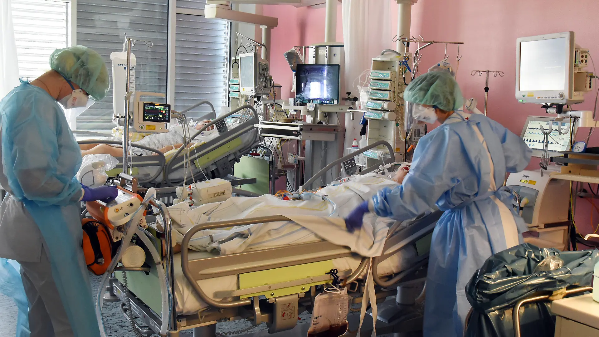 31.03.2021, Sachsen, Leipzig: Auf der Covid-19-Station, einem Bereich der Operativen Intensivstation vom Universitätsklinikum Leipzig, bereiten eine Ärztin (l) und eine Schwester einen Patienten für eine Untersuchung vor. Auf der Intensivstation wächst seit Tagen die Zahl der Corona-Erkrankten mit schweren Verläufen, darunter immer mehr jüngere Patenten zwischen 30 und 60 Jahren. Foto: Waltraud Grubitzsch/dpa-Zentralbild/dpa +++ dpa-Bildfunk +++