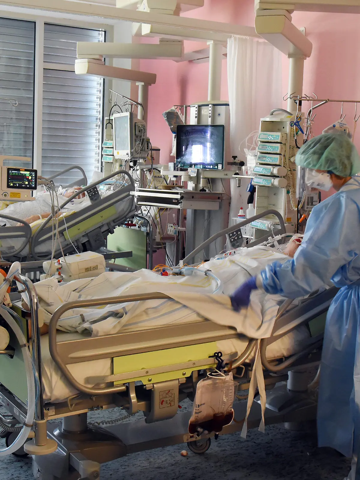 31.03.2021, Sachsen, Leipzig: Auf der Covid-19-Station, einem Bereich der Operativen Intensivstation vom Universitätsklinikum Leipzig, bereiten eine Ärztin (l) und eine Schwester einen Patienten für eine Untersuchung vor. Auf der Intensivstation wächst seit Tagen die Zahl der Corona-Erkrankten mit schweren Verläufen, darunter immer mehr jüngere Patenten zwischen 30 und 60 Jahren. Foto: Waltraud Grubitzsch/dpa-Zentralbild/dpa +++ dpa-Bildfunk +++