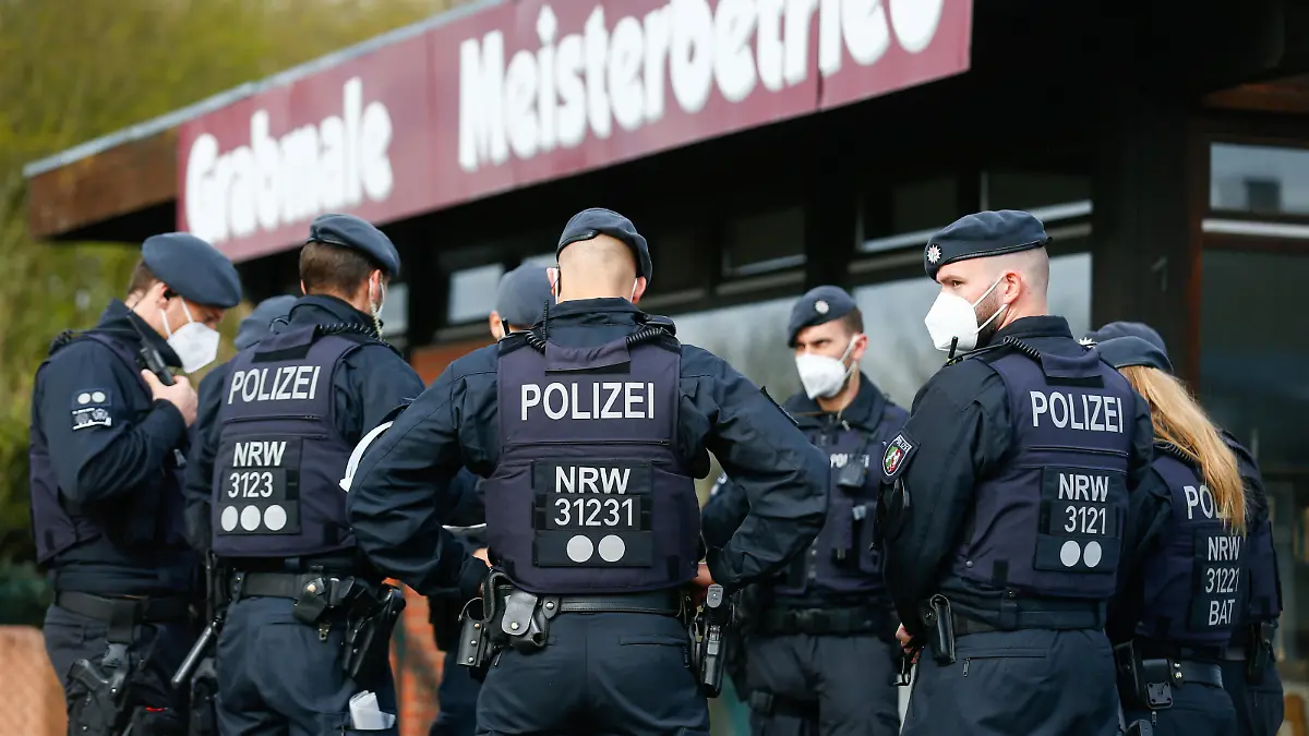 Police officers secure a cemetery while members and guests of the Goman clan wait to enter the funeral of one of the clan's chiefs, as only 25 people are allowed to attend due to coronavirus disease (COVID-19) restrictions, in Leverkusen, Germany, April 9, 2021. REUTERS/Thilo Schmuelgen