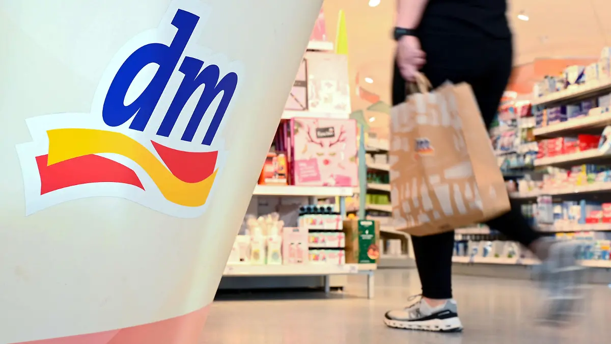 Eine Person geht in einer Filiale der Drogeriemarktkette dm mit einer Einkaufstüte am Kassenbereich vorbei. Am 10.11.2022 findet die Jahres-Pressekonferenz des Drogeriekonzerns statt.