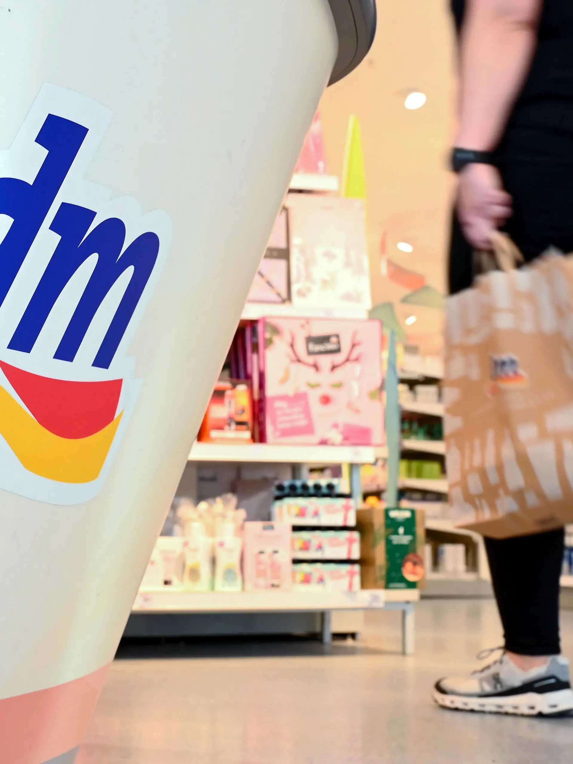 Eine Person geht in einer Filiale der Drogeriemarktkette dm mit einer Einkaufstüte am Kassenbereich vorbei. Am 10.11.2022 findet die Jahres-Pressekonferenz des Drogeriekonzerns statt.