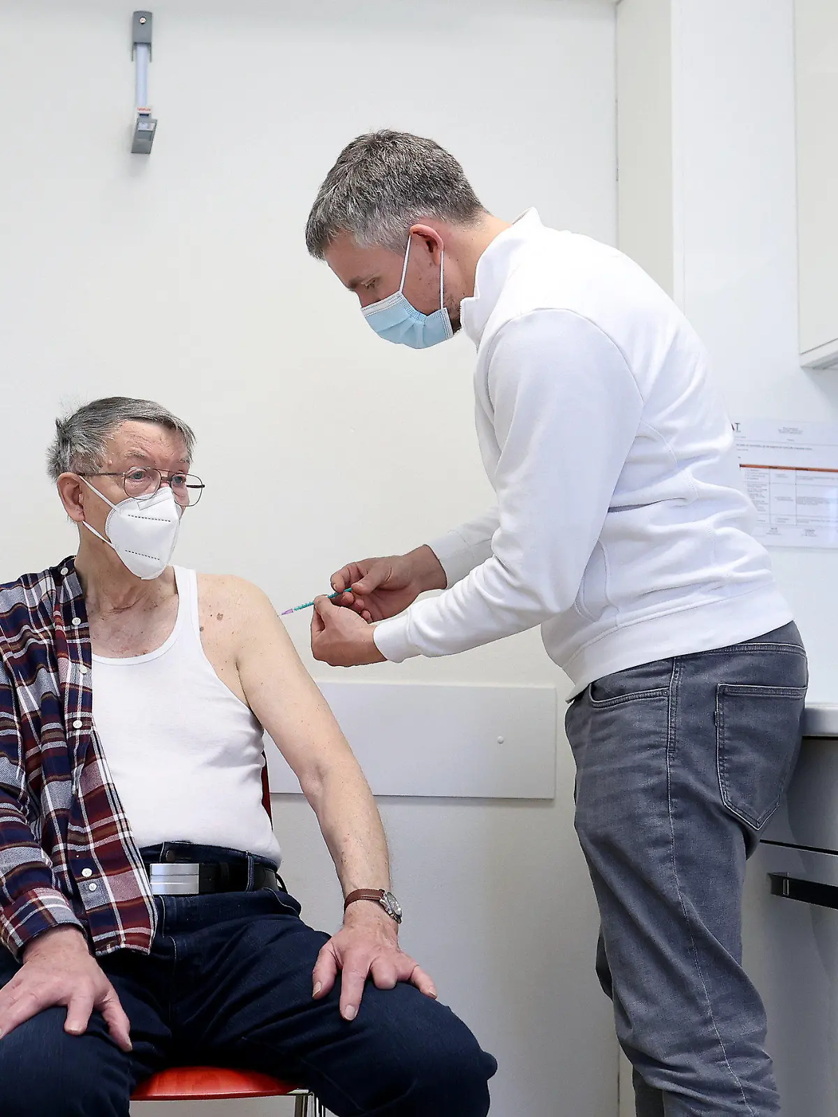 07.04.2021, Sachsen-Anhalt, Schönebeck: Der Hausarzt Robin John (r) verabreicht dem 85-jährigen Hans-Joachim Nettelbeck in einem Behandlungszimmer die erste Impfung mit dem Corona-Impfstoff Comirnaty von Biontech/Pfizer. In Sachsen-Anhalt werden die niedergelassenen Ärzte in die Impfstrategie einbezogen. Foto: Ronny Hartmann/dpa +++ dpa-Bildfunk +++
