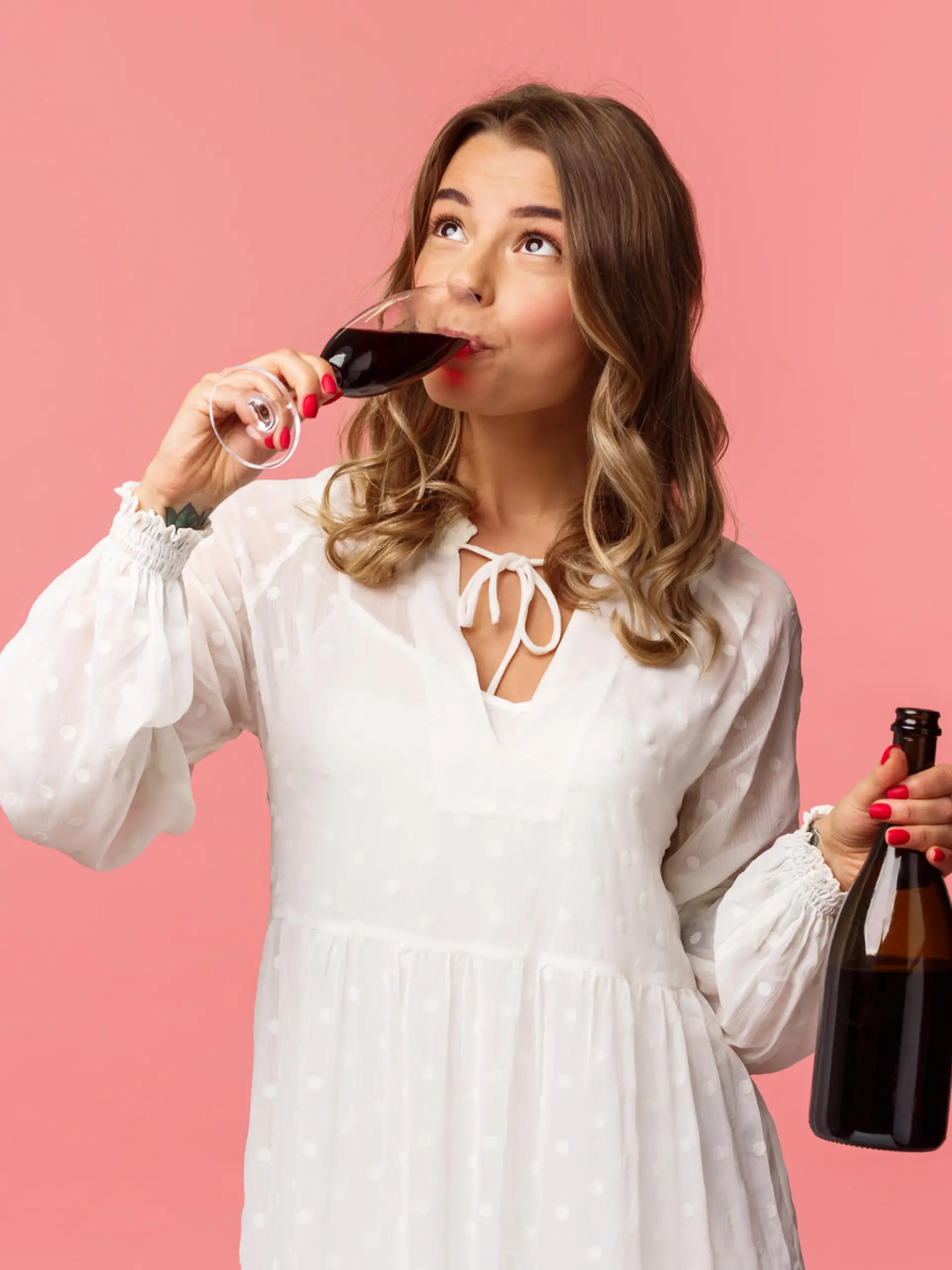 Holidays, spring and party concept. Portrait of young elegant happy blond woman, wear white trendy dress, drinking wine from glass looking up pleased, tasting good drink, hold bottle. (Holidays, spring and party concept. Portrait of young elegant hap
