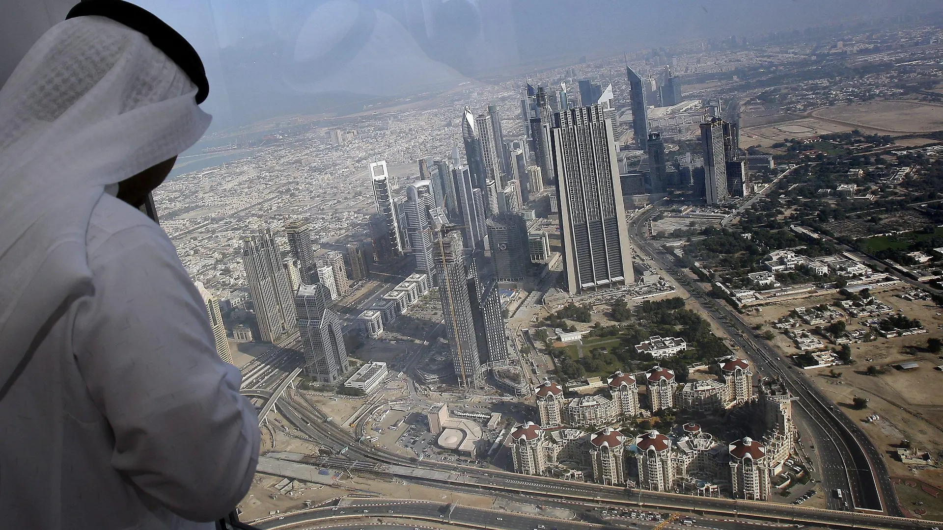 A man has a view of Dubai city from floor 124 of Burj Dubai the supertall skyscraper during a media tour in Dubai, United Arab Emirates, 04 January 2010. Burj Dubai, the world's tallest building, will open 04 January in a carefully orchestrated ceremony before a crowd of thousands. Developed by Emaar Properties, Burj Dubai is the focal point of the 500-acre master planned community Downtown Burj Dubai.The exact height of the superscraper ? known as the Burj Dubai ? has remained a closely guarded secret although it is known to be 818 metres. EPA/ALI HAIDER +++(c) dpa - Bildfunk+++
