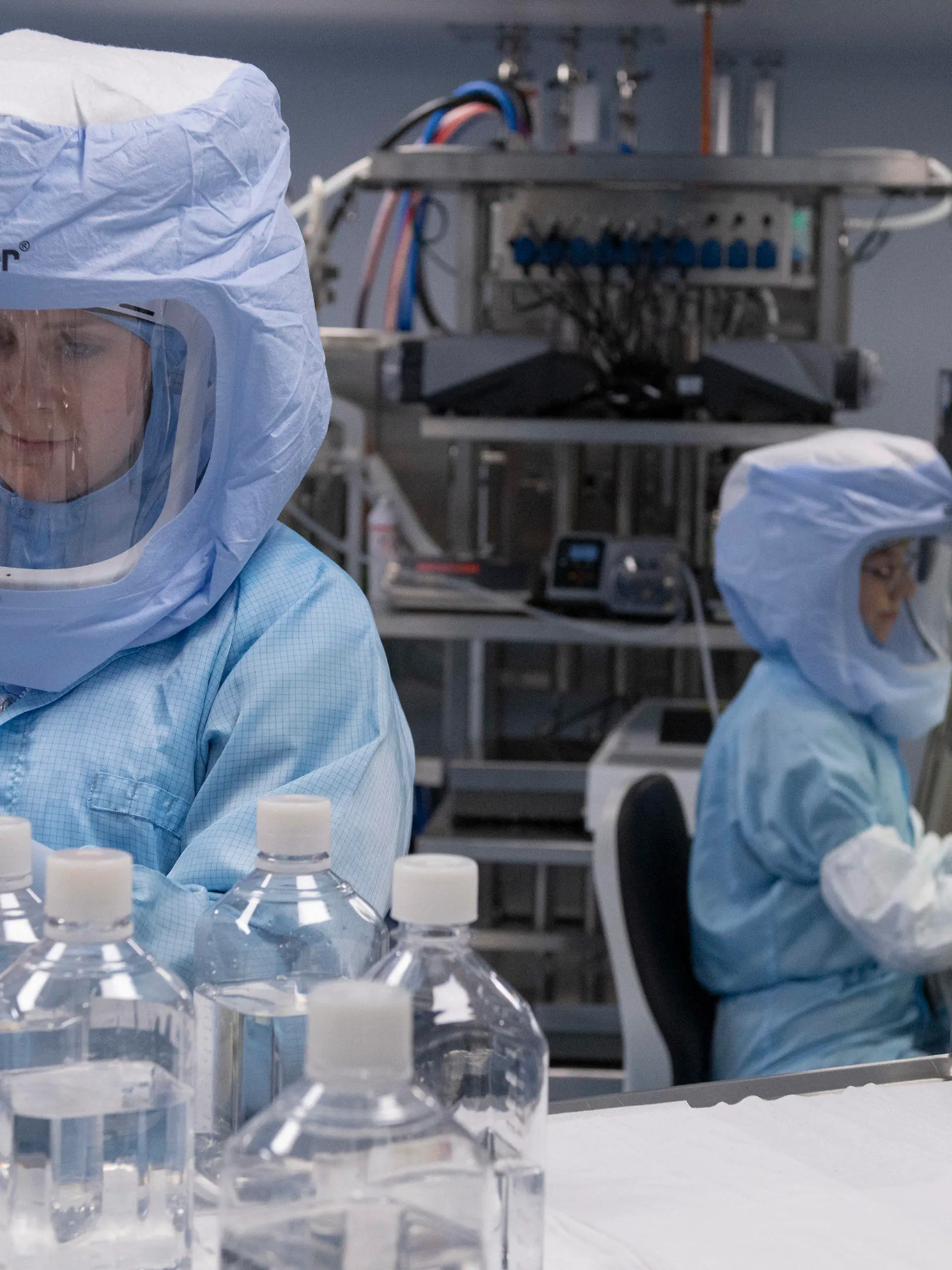 27.03.2021, Hessen, Marburg: Mit Ganzkörper-Schutzanzügen simulieren Laborantinnen der Firma Biontech in einem Reinraum am neuen Produktionsstandort in Marburg die finalen Arbeitsschritte zur Herstellung des Corona-Impfstoffes an einem Bioreaktor. Nach früheren Angaben des Unternehmens sollen im ersten Halbjahr 2021 in Marburg 250 Millionen Dosen des Impfstoffs von Biontech und seines US-Partners Pfizer hergestellt werden. Sobald das Werk in Marburg voll betriebsbereit ist, will die Firma dort 750 Millionen Dosen des COVID-19-Impfstoffs jährlich herstellen. Foto: Boris Roessler/dpa +++ dpa-Bildfunk +++