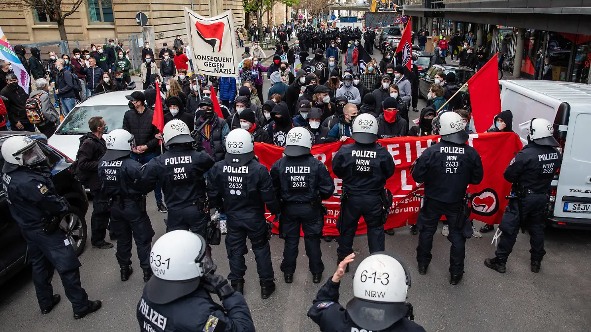 03.04.2021, Baden-Württemberg, Stuttgart: Linke Demonstranten stehen Einsatzkräften der Polizei gegenüber. Die Demo der Linken richtet sich gegen die zeitgleich laufende Demonstration der Initiative «Querdenken». Die Demonstration der Querdenker richtet sich gegen die Pandemie-Einschränkungen der Bundesregierung - Abstandsregeln und das tragen von Masken wurde größtenteils missachtet. Foto: Christoph Schmidt/dpa +++ dpa-Bildfunk +++