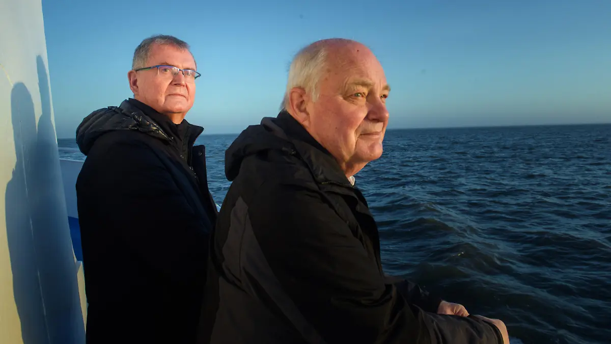 30.03.2021, Schleswig-Holstein, Hooge: Urs Philipzig (l), Mediziner aus Bredstedt und neuer Arzt von Hallig Hooge, und Gerhard Steinort (r), Mediziner in Langenhorn und ehemaliger Arzt der Hallig Hooge, stehen während des Sonnenaufgangs am Heck der MS Seeadler auf dem Weg zur Hallig Hooge. (zu dpa «Hooges Halligarzt geht in den Ruhestand») Foto: Gregor Fischer/dpa +++ dpa-Bildfunk +++