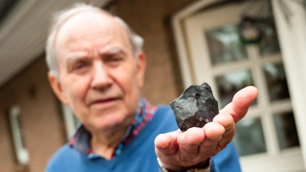 28.04.2023, Schleswig-Holstein, Elmshorn: Wilfried Labusch, Hausbesitzer, hält vor seinem Haus einen kleinen Meteoriten, der niedergegangen ist. Der Gesteinsbrocken von der Größe eines Tennisballs habe das Dach eines Hauses durchschlagen, dem Deutschen Zentrum für Luft- und Raumfahrt zufolge ist ein solches Ereignis sehr selten. (zu dpa ·Kleiner Meteorit trifft Haus in Schleswig-Holstein·) Foto: Daniel Bockwoldt/dpa/Daniel Bockwoldt +++ dpa-Bildfunk +++