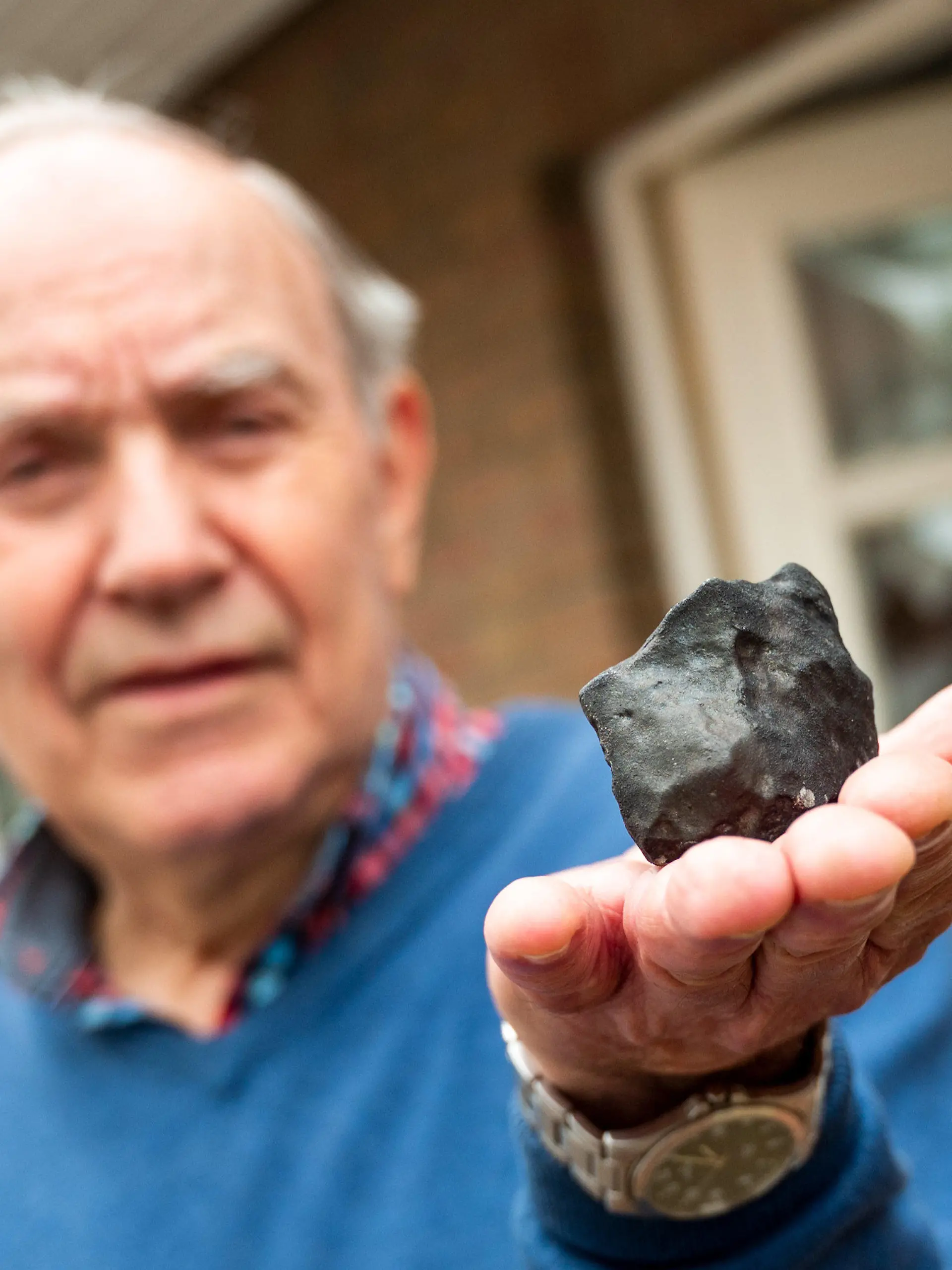 28.04.2023, Schleswig-Holstein, Elmshorn: Wilfried Labusch, Hausbesitzer, hält vor seinem Haus einen kleinen Meteoriten, der niedergegangen ist. Der Gesteinsbrocken von der Größe eines Tennisballs habe das Dach eines Hauses durchschlagen, dem Deutschen Zentrum für Luft- und Raumfahrt zufolge ist ein solches Ereignis sehr selten. (zu dpa ·Kleiner Meteorit trifft Haus in Schleswig-Holstein·) Foto: Daniel Bockwoldt/dpa/Daniel Bockwoldt +++ dpa-Bildfunk +++
