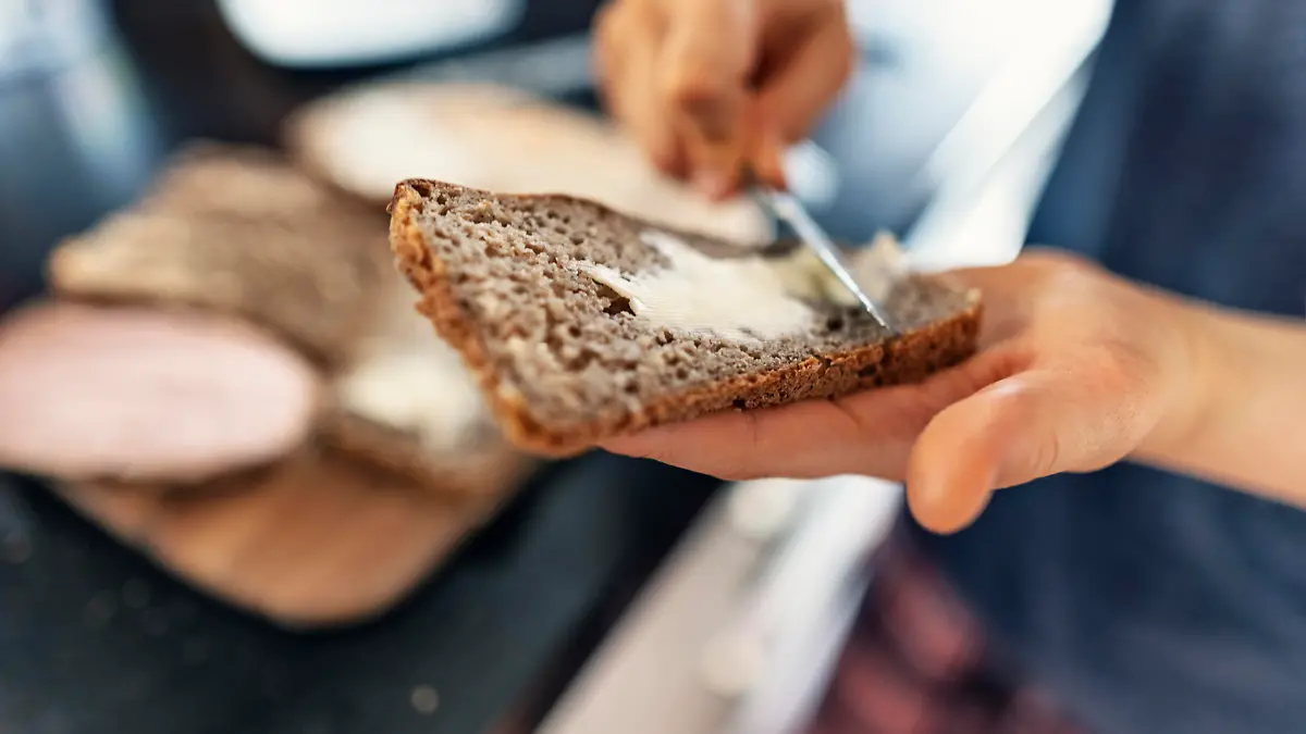 Teenage boy helping to prepare supper for the family. The boy is buttering a fresh slice of delicious sourdough rye bread.
Canon R5
