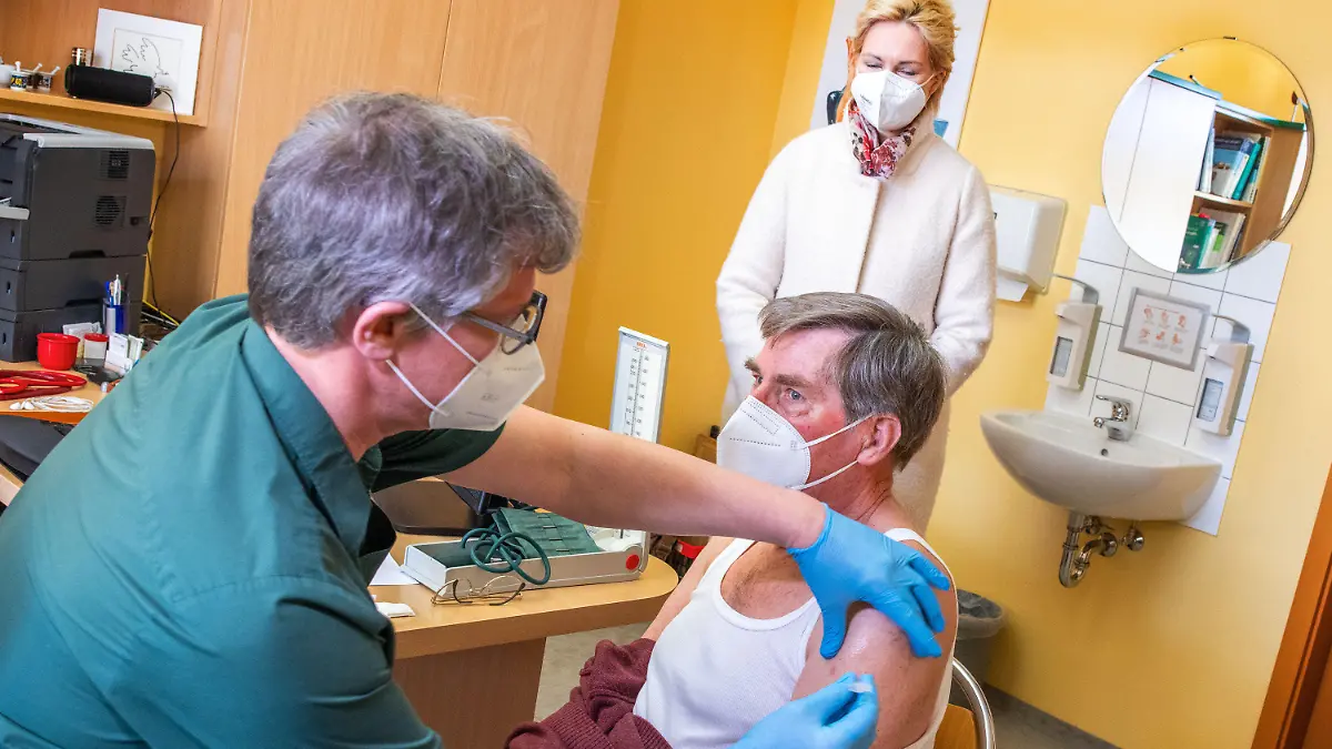 26.03.2021, Mecklenburg-Vorpommern, Neubukow: Manuela Schwesig (SPD), die Ministerpräsidentin von Mecklenburg-Vorpommern, beobachtet in der Hausarztpraxis von Stefan Zutz das Impfen des 79-jährigen Patienten Dietrich Peters mit dem Corona-Impfstoff AstraZeneca. Das landesweite Impfen bei den Hausärzten startet in Mecklenburg-Vorpommern, zunächst werden Starterpakete eingesetzt, mit denen sich das medizinische Personal schützen kann. Zusätzlich können damit in den Hausarztpraxen einige besonders gefährdete Patienten geimpft werden. Foto: Jens Büttner/dpa-Zentralbild/dpa +++ dpa-Bildfunk +++