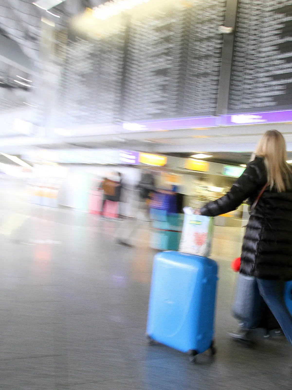  Eine Reisende geht mit ihrem Gepäck unter der Anzeigetafel in der Abflughalle B im Flughafen Frankfurt, Hessen, Deutschland *** A traveler walks with her luggage under the display board in Departure Hall B at Frankfurt Airport, Hesse, Germany