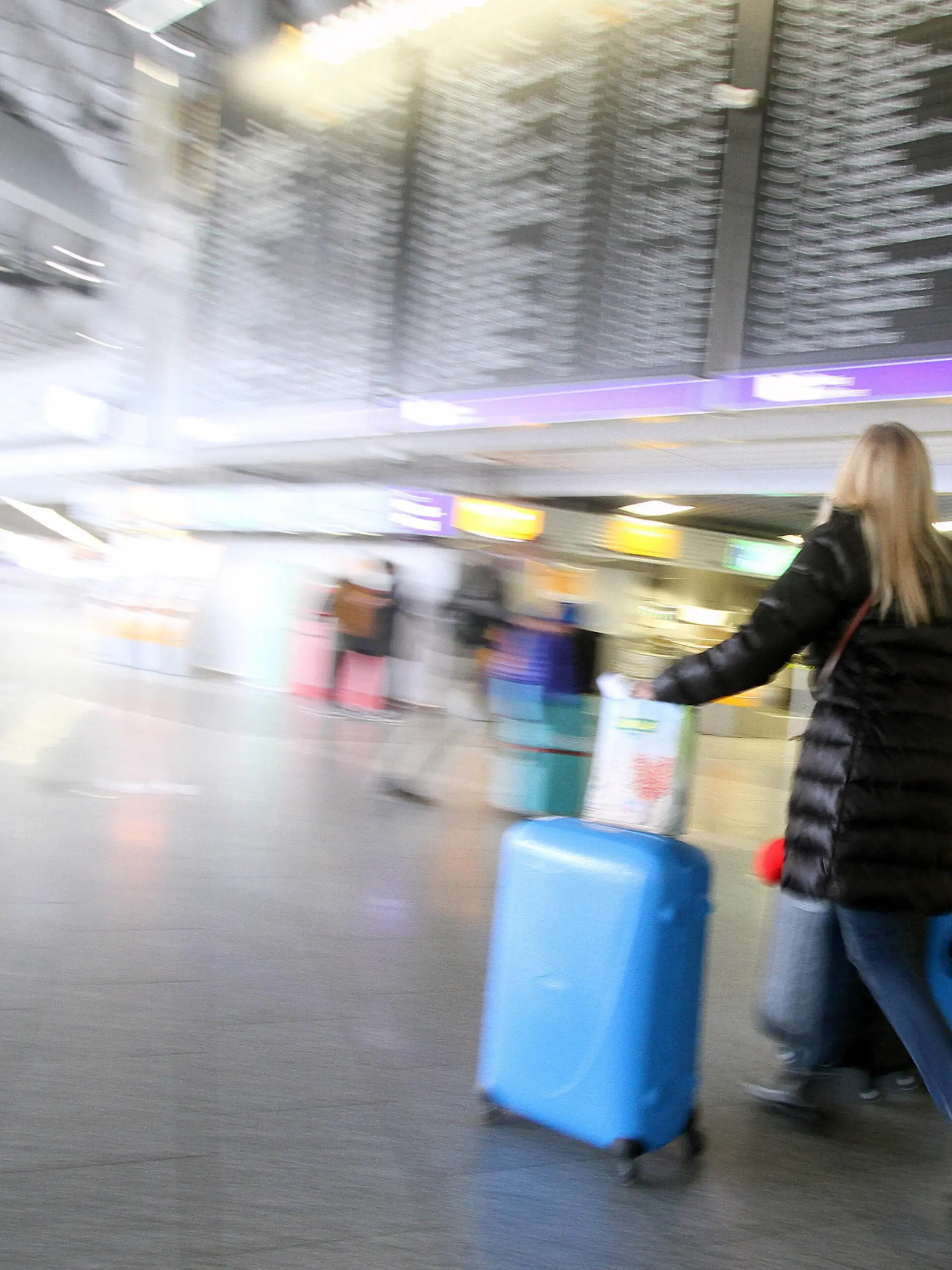  Eine Reisende geht mit ihrem Gepäck unter der Anzeigetafel in der Abflughalle B im Flughafen Frankfurt, Hessen, Deutschland *** A traveler walks with her luggage under the display board in Departure Hall B at Frankfurt Airport, Hesse, Germany