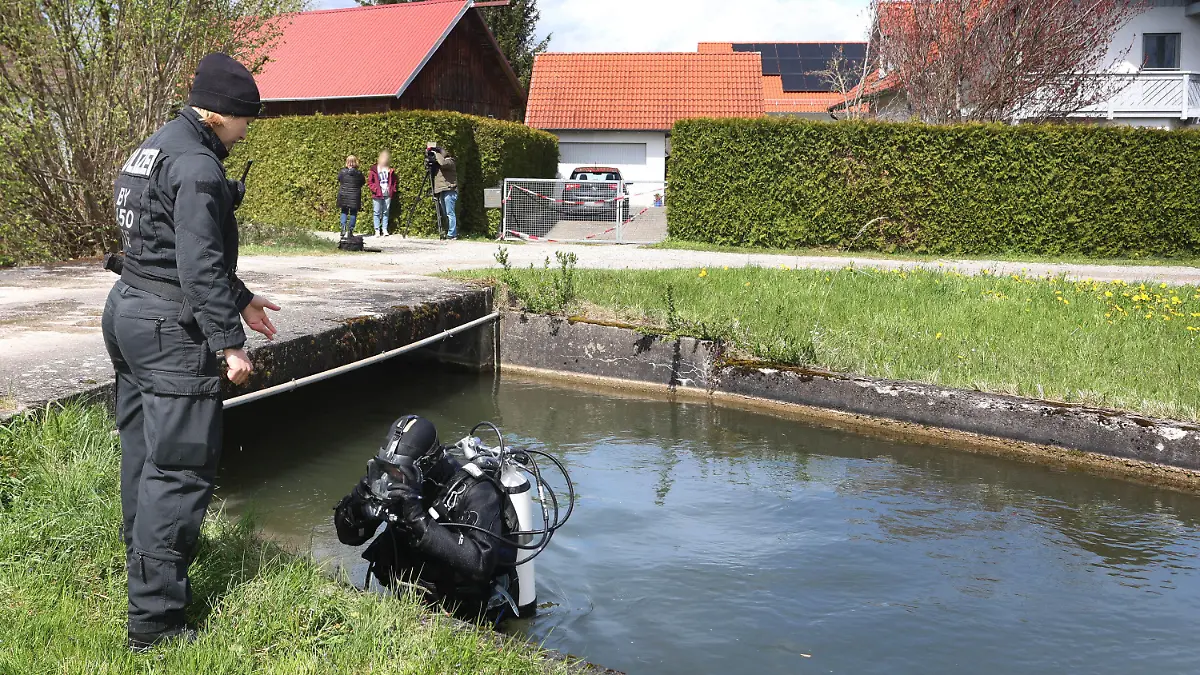 24.04.2023, Bayern, Altenstadt An Der Iller: Ein Polizeitaucher steigt vor einem Einfamilienhaus aus dem Wasser des Mühlbachs. Am Samstag wurden die Leichen eines Ehepaars in dem Haus entdeckt. Die Polizei geht davon aus, dass die beiden getötet wurden. Foto: Karl-Josef Hildenbrand/dpa - ACHTUNG: Person(en) wurde(n) aus rechtlichen Gründen gepixelt +++ dpa-Bildfunk +++