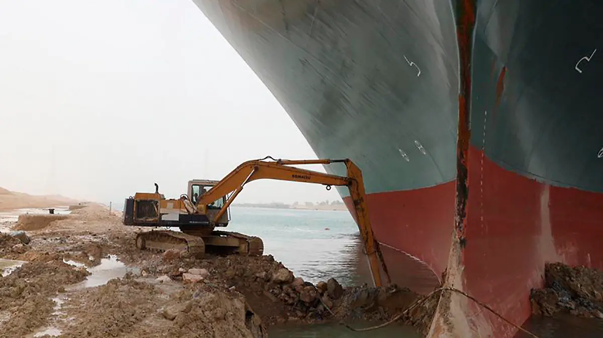 REMOVES REFERENCE TO BACKHOE - A work crew using excavating equipment tries to dig out the Ever Given, a Panama-flagged cargo ship, that is wedged across the Suez Canal and blocking traffic in the vital waterway. An operation is underway to try to work free the ship, which further imperiled global shipping Thursday as at least 150 other vessels needing to pass through the crucial waterway idled waiting for the obstruction to clear. (Suez Canal Authority via AP)