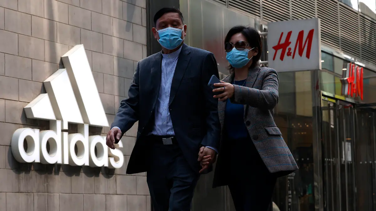 Visitors to a mall shopping area pass by Adidas and H&M stores in Beijing, Thursday, March 25, 2021. China's ruling Communist Party is lashing out at H&M and other clothing and footwear brands as it retaliates for Western sanctions imposed on Chinese officials accused of human rights abuses in the northwestern region of Xinjiang. (AP Photo/Ng Han Guan)