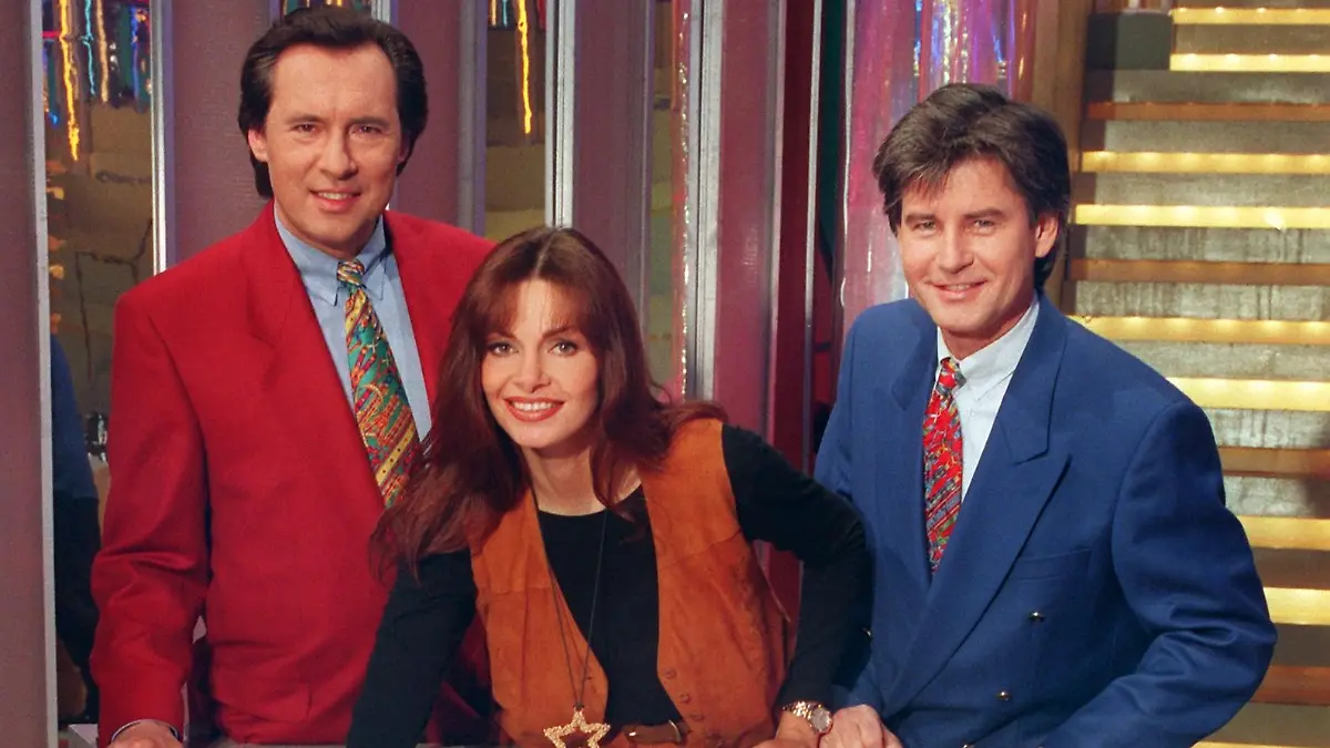 Maren Gilzer, Peter Bond (l) und Frederic Meisner posieren am 10.2.1994 im neuen Studio an der Glücksrad-Scheibe für die Fotografen. Die erfolgreichste deutsche Gameshow ist umgezogen. Seit dem 4. Februar wird die Sendung aus dem neuen und größeren Studio auf dem Gelände des ehemaligen DDR-Fernsehens in Berlin Adlershof ausgestrahlt.
