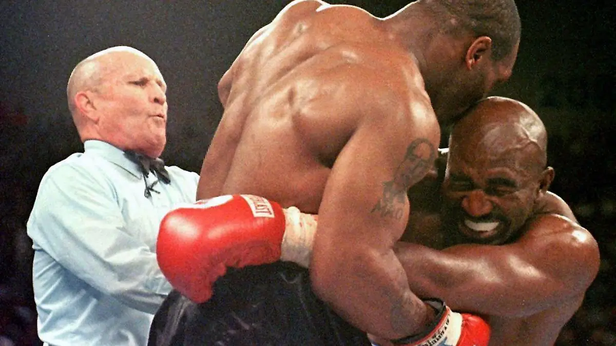 Mit einem der größten Skandale der Boxgeschichte endet am 28.6.1997 in Las Vegas der Rückkampf zwischen Schwergewichts-Weltmeister Evander Holyfield (r.) und Mike Tyson M./beide USA). Ringrichter Lane Mills (l.) geht dazwischen, nachdem Tyson Holyfield in der dritten Runde gleich zweimal ins Ohr gebissen hat. Tyson wird nach dieser Runde disqualifiziert. Siebeneinhalb Monate nach seinem Sensationssieg durch technischen K.o. im ersten Kampf verteidigt der 34jährige Holyfield damit seinen WM-Titel des Boxverbandes WBA. Tyson droht eine lebenslange Sperre, seine Börse von umgerechnet 50 Millionen Mark wurde eingefroren.
