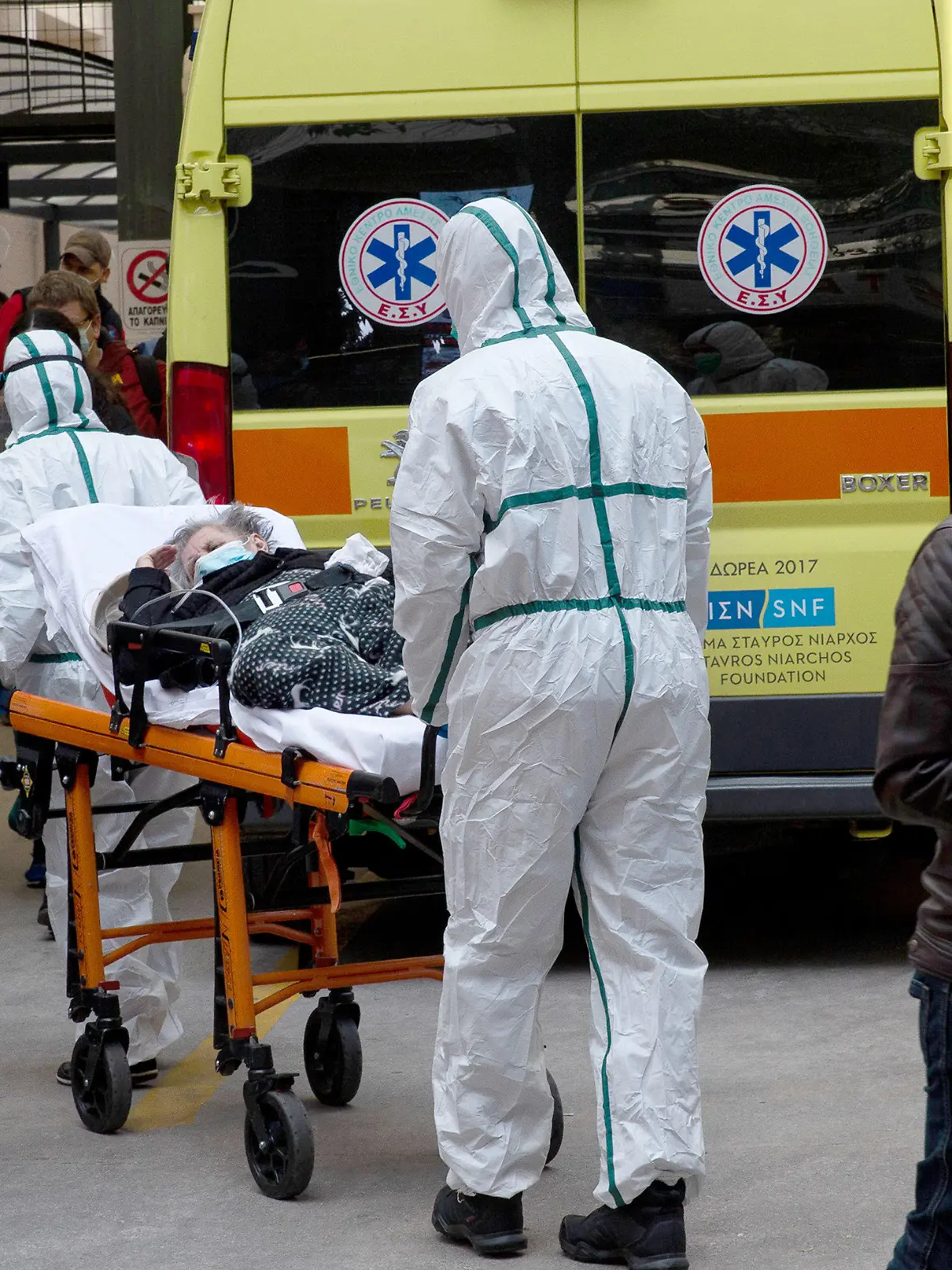 11.03.2021, Griechenland, Athen: Medizinische Mitarbeiter in Schutzausrüstung transportieren einen Patienten auf einer Trage, um ihn in einem Krankenhaus in Athen zu verlegen. Foto: Marios Lolos/Xinhua/dpa +++ dpa-Bildfunk +++