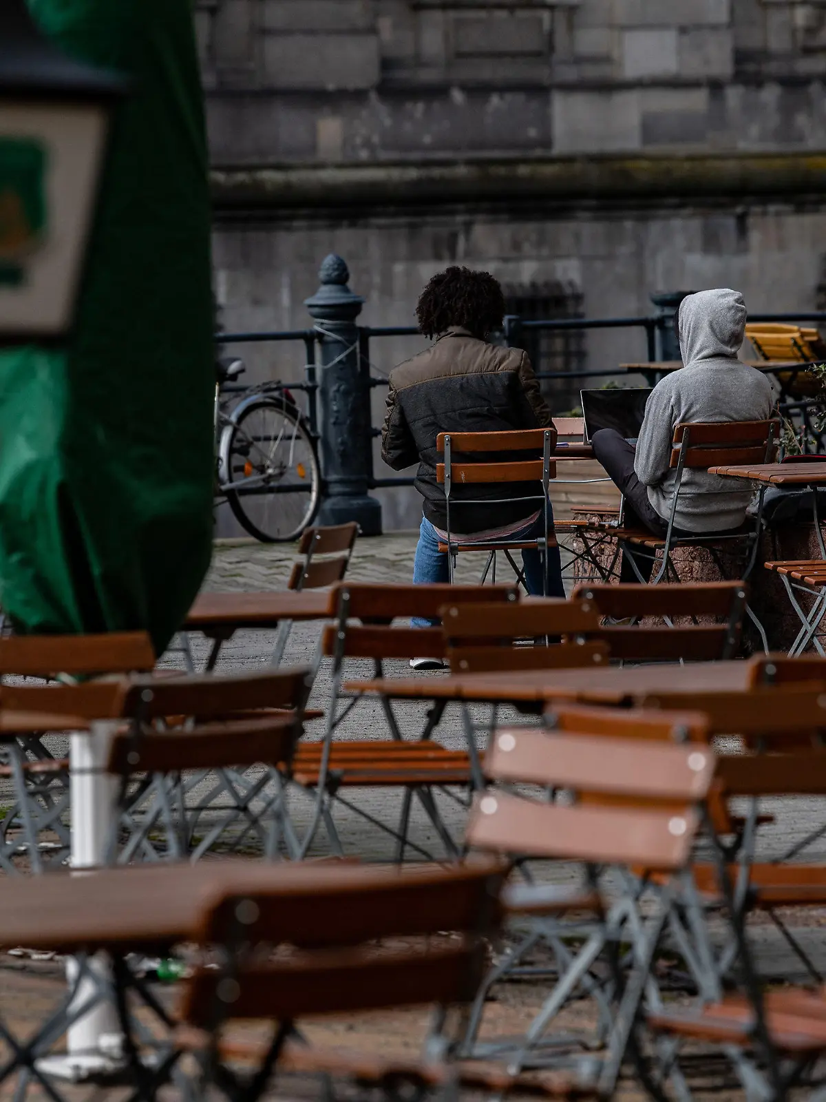 18.03.2021, Berlin: Zwei Männer sitzen auf Stühlen einer geschlossenen Außengastronomie im Nikolaiviertel. Aufgrund der Corona-Pandemie sind derartige Betriebe bis auf weiteres geschlossen. Foto: Paul Zinken/dpa-Zentralbild/dpa +++ dpa-Bildfunk +++