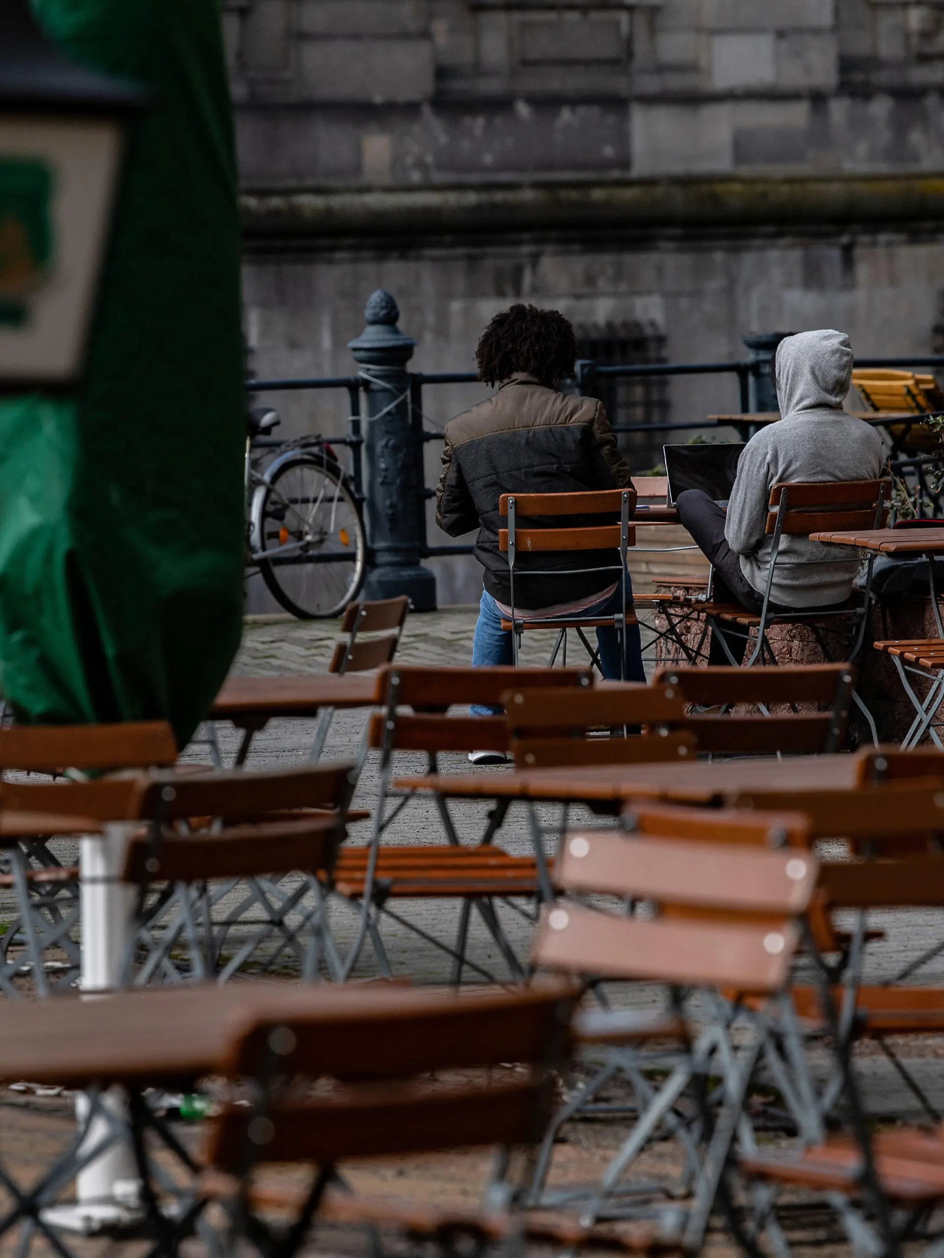 18.03.2021, Berlin: Zwei Männer sitzen auf Stühlen einer geschlossenen Außengastronomie im Nikolaiviertel. Aufgrund der Corona-Pandemie sind derartige Betriebe bis auf weiteres geschlossen. Foto: Paul Zinken/dpa-Zentralbild/dpa +++ dpa-Bildfunk +++