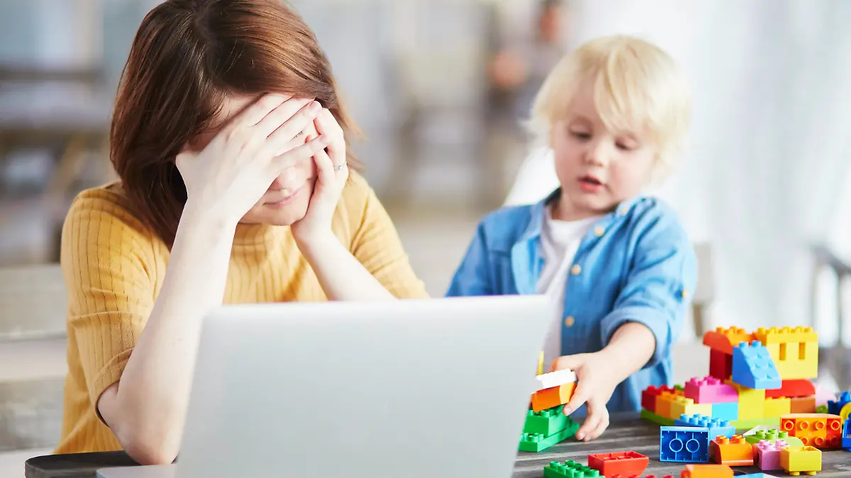 Der Sohn spielt mit Bausteinen, während die Mutter am Computer arbeitet