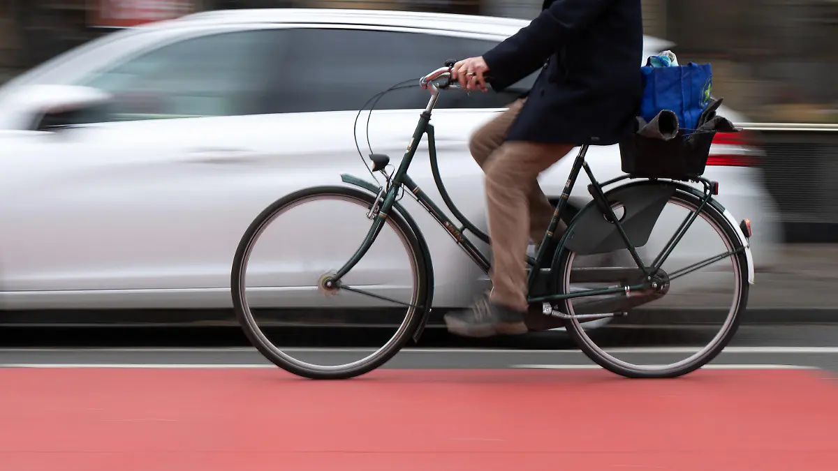 PRODUKTION - 14.03.2023, Hessen, Frankfurt/Main: Ein Fahrradfahrer fährt auf einer Fahrradstraße an einem Schutzstreifen für geöffnete Türen an Autos vorbei. (Wischeffekt durch Langzeitbelichtung) Der Schutzstreifen soll verhindern, dass Fahrradfahrer durch unachtsam geöffnete Türen verletzt werden. (zu dpa: Forderung nach mehr Sicherheit für Radfahrer gegen «Dooring»-Gefahr) Foto: Sebastian Gollnow/dpa +++ dpa-Bildfunk +++