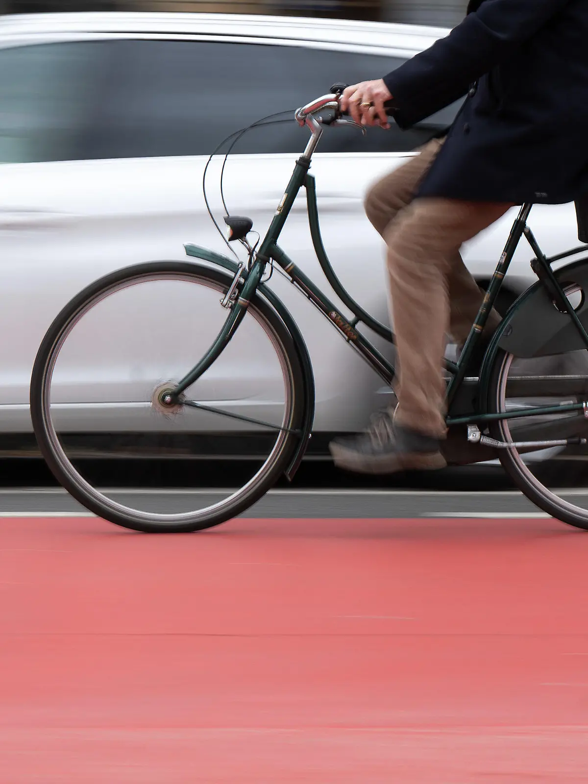 PRODUKTION - 14.03.2023, Hessen, Frankfurt/Main: Ein Fahrradfahrer fährt auf einer Fahrradstraße an einem Schutzstreifen für geöffnete Türen an Autos vorbei. (Wischeffekt durch Langzeitbelichtung) Der Schutzstreifen soll verhindern, dass Fahrradfahrer durch unachtsam geöffnete Türen verletzt werden. (zu dpa: Forderung nach mehr Sicherheit für Radfahrer gegen «Dooring»-Gefahr) Foto: Sebastian Gollnow/dpa +++ dpa-Bildfunk +++