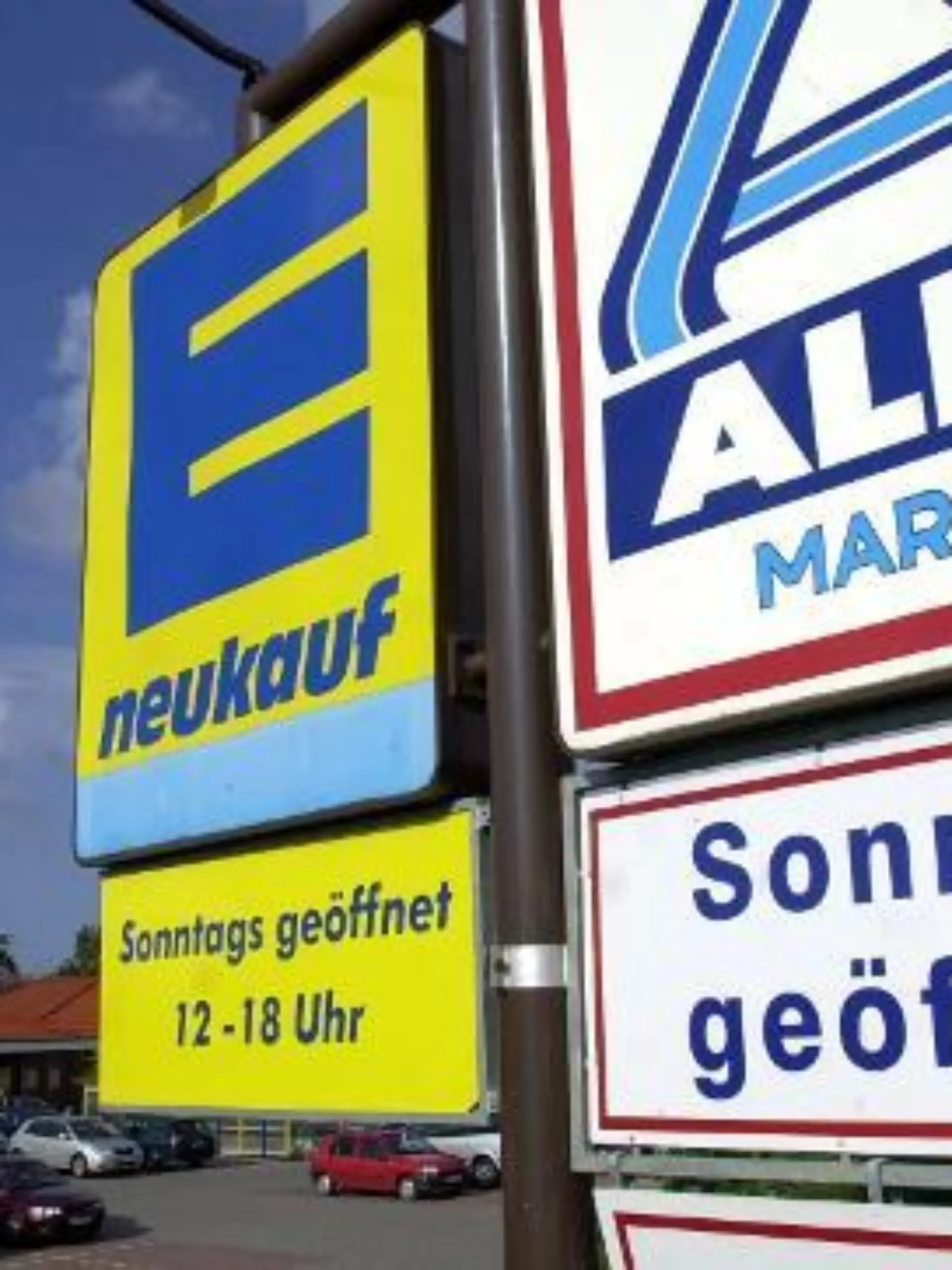 Die Schilder von Edeka und Aldi Nord werben im Seebad Heringsdorf auf der Insel Usedom für den Einkauf am Sonntag (aufgenommen am 28.06.2004). In der Sommersaison nutzen auch die Supermärkte in Mecklenburg-Vorpommern die "Bäder- und Fremdenverkehrsregelung". Die auf die Jahre 2003 bis 2006 befristete Ausnahmebewilligung ermöglicht es einzelnen Gemeinden, im Zeitraum vom 01. Februar bis 30. November mögliche Geschäftsöffnungszeiten samstags bis 20.00 Uhr und sonn- und feiertags von 12.00 Uhr bis 18.30 Uhr anzubieten. Ausgenommen sind bestimmte Feiertage. Foto: Stefan Sauer dpa