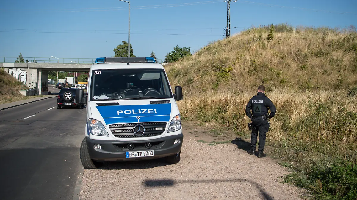 26.07.2018, Thüringen, Erfurt: Polizisten stehen an einem Gleisabschnitt in Richtung Weimar. Seit Donnerstagmorgen sucht die Polizei einen mutmaßlichen Messerstecher. Auch der Zugverkehr in Richtung Weimar wurde unterbrochen. Foto: Arne Immanuel Bänsch/dpa +++ dpa-Bildfunk +++