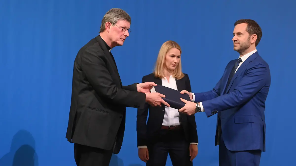 Lawyer Kerstin Stirner (C) looks on as Bjoern Gercke (R), an attorney mandated by the Church, hands over to Cologne's archbishop Rainer Maria Woelki a report on abuse by clergy during a news conference, in Cologne, Germany March 18, 2021. Ina Fassbender/Pool via REUTERS