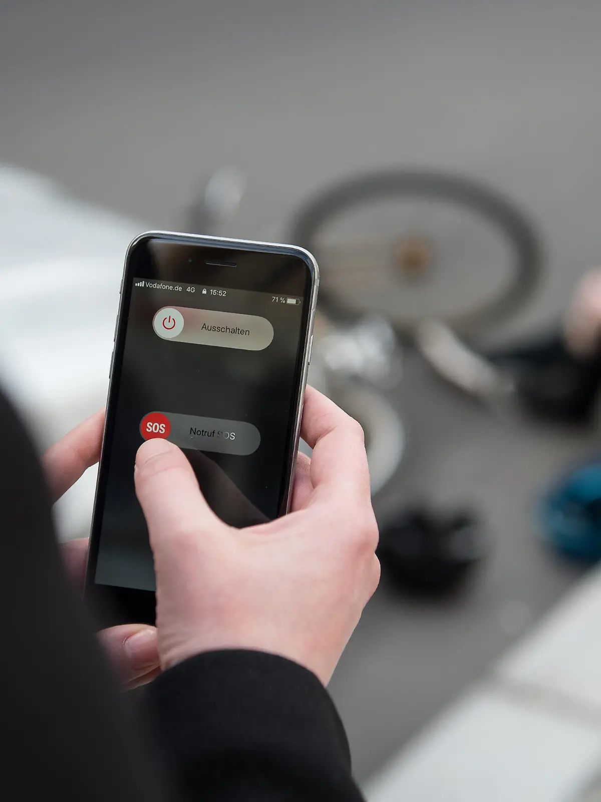 Eine Frau setzt einen Notruf mit einem Smartphone ab, nachdem ein Mann einen Fahrradunfall hatte. (Szene gestellt)
