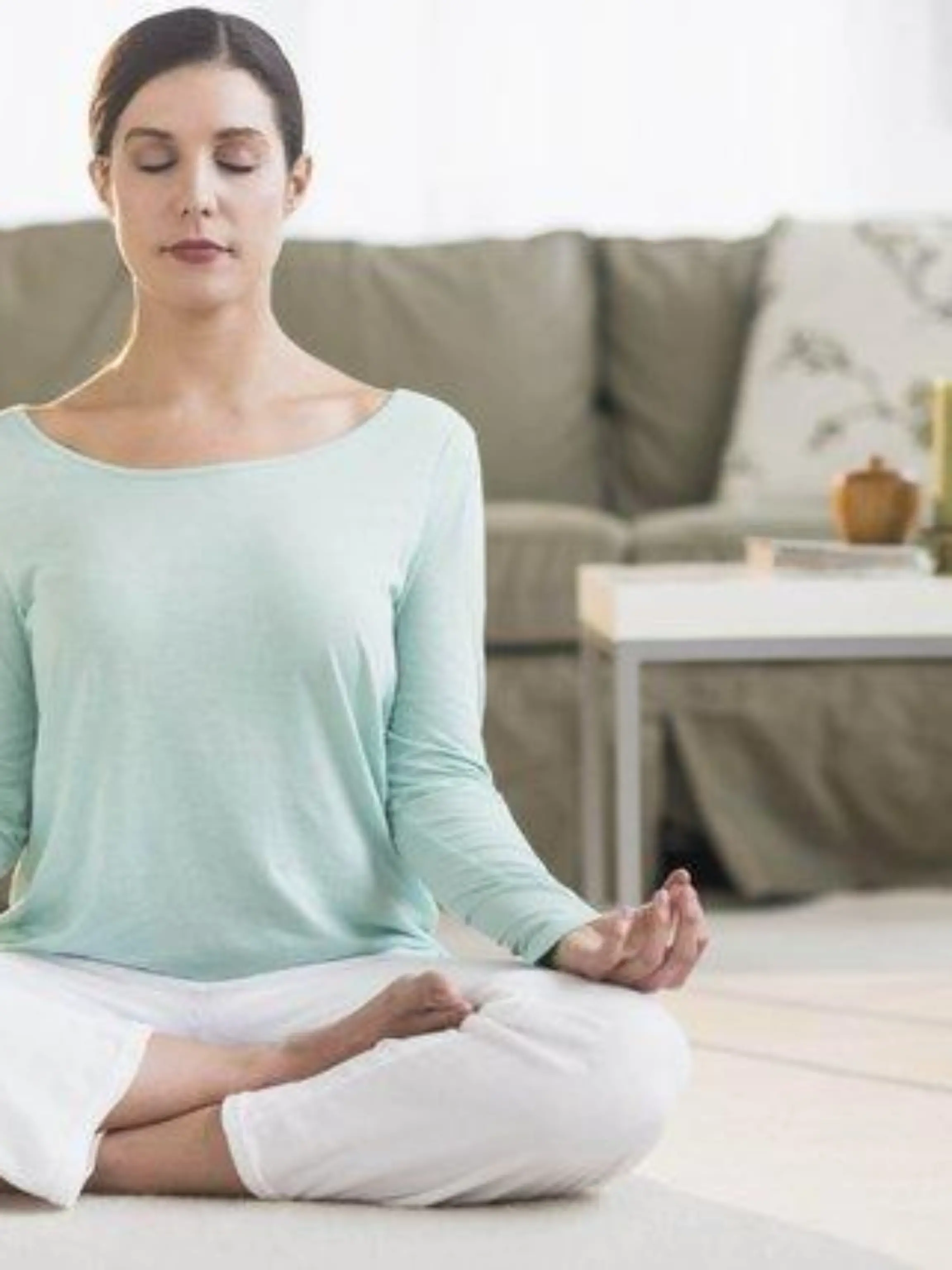 Woman meditating in living room Keine Weitergabe an Drittverwerter.