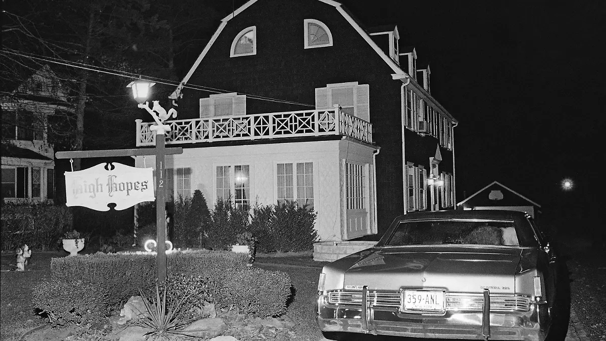 FILE - In this Nov. 14, 1974 file photo, police and members of the Suffolk County Coroner's Office investigate the murder of six people found shot in Amityville, N.Y. Ronald DeFeo, Jr., the man convicted of slaughtering his parents and four siblings in a home that later inspired the book and movie "The Amityville Horror" died Friday, March 12, 2021 at Albany Medical Center, where he was taken Feb. 2 from a prison in New York’s Catskill Mountains, prison officials said Monday, March 15. He was 69. (AP Photo/Richard Drew, File)