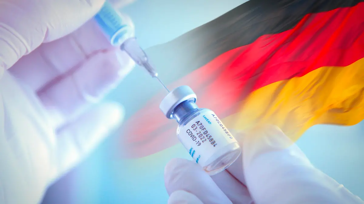 Arzt mit Corona-Impfspritze vor Deutschlandfahne