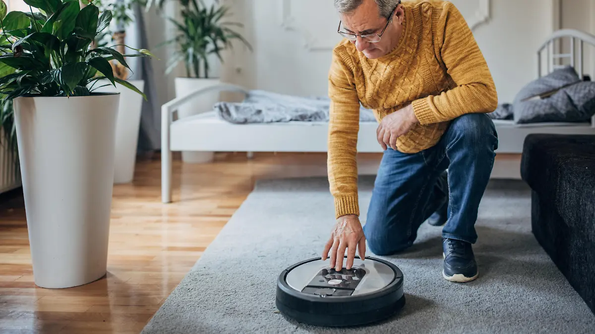 A senior uses a robotic vacuum cleaner