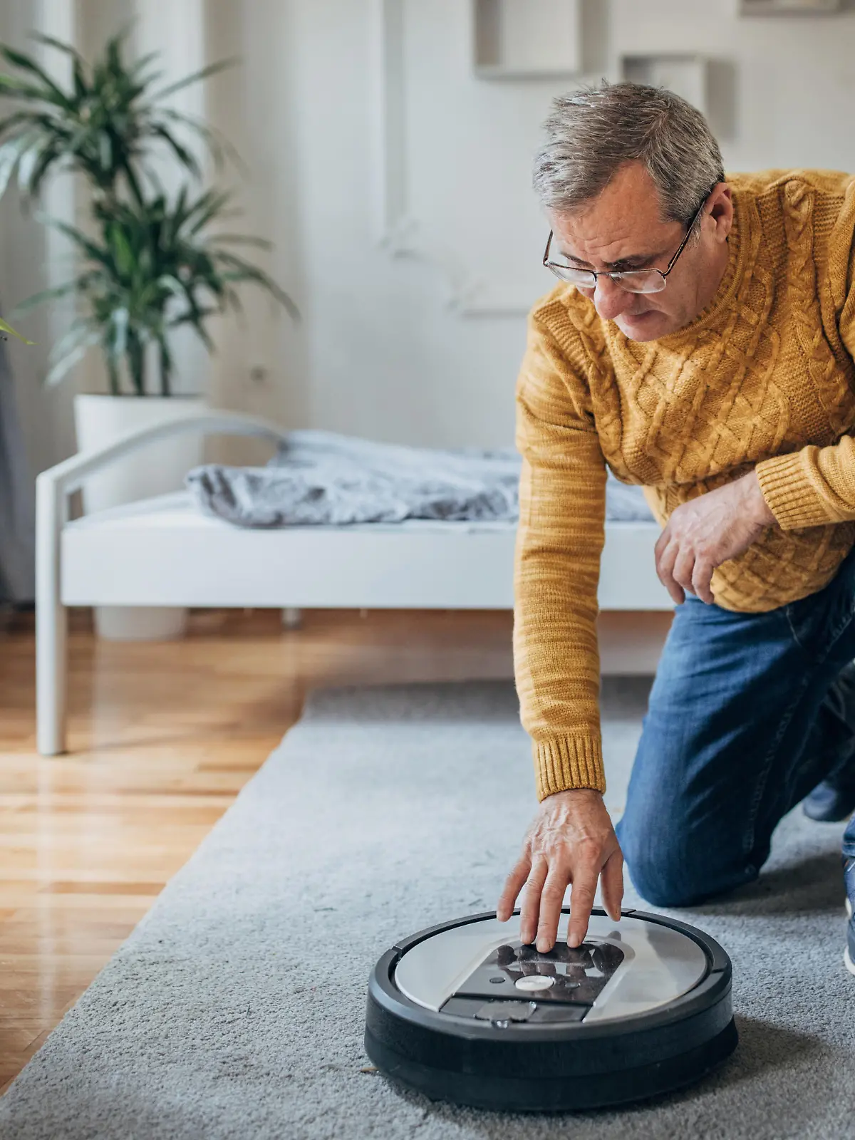 A senior uses a robotic vacuum cleaner