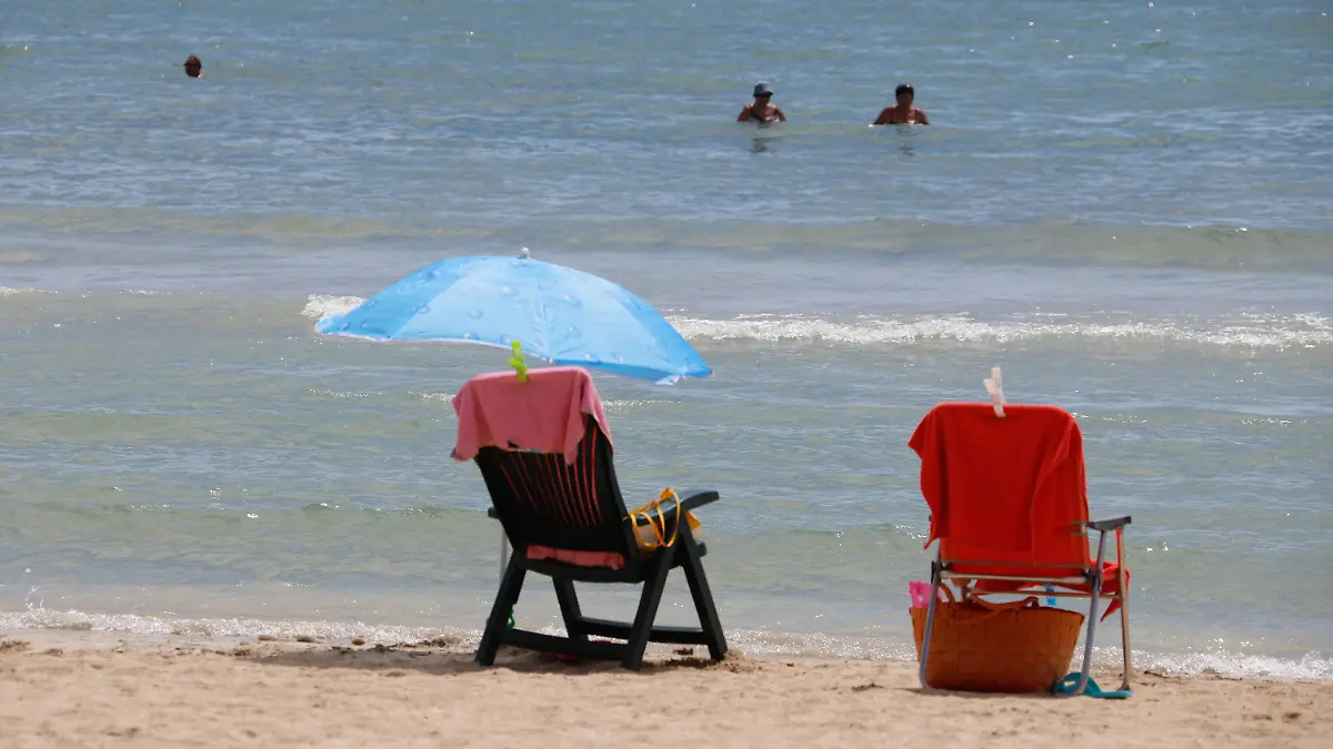 ARCHIV - 18.08.2020, Spanien, Palma: Touristen schwimmen Am Strand Can Pastilla in Palma de Mallorca stehen mit Handtüchern bedeckte Stühle, während Touristen im Meer schwimmen. (Illustration zu dpa: "Verbraucherschutzminister will Vorkasse bei Reisen abschaffen") Foto: Clara Margais/dpa +++ dpa-Bildfunk +++