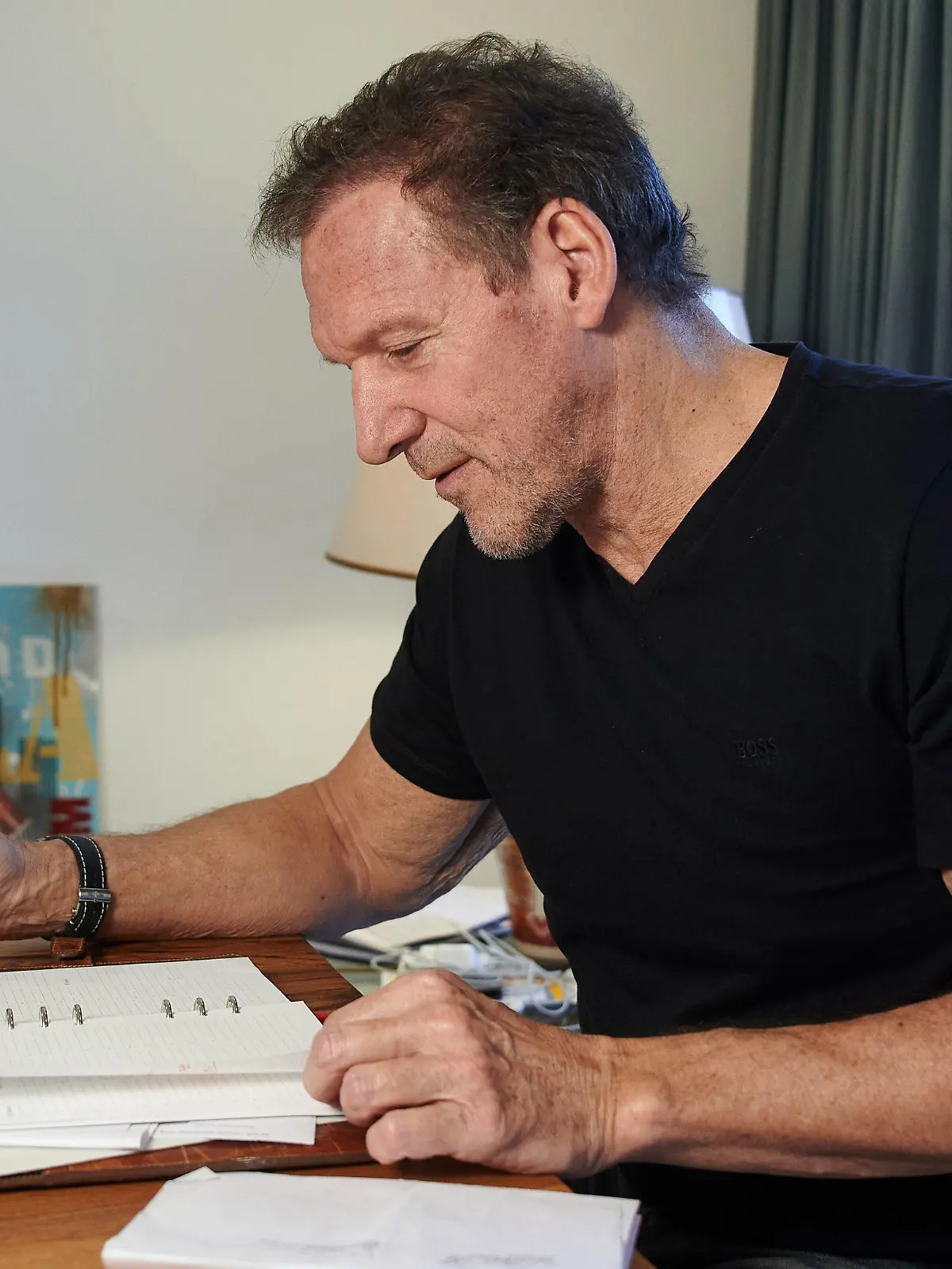 03.02.2021, Nordrhein-Westfalen, Recklinghausen: Der Schauspieler Ralf Moeller schaut während eines Interviews mit der Deutschen Presse-Agentur in seinem Wohnzimmer in seinen Terminkalender. Moeller, der normalerweise überwiegend in den USA lebt, kümmert sich seit Monaten um seine Eltern und will sich um deren Impfung gegen das Coronavirus kümmern. (zu dpa «Schauspieler Ralf Moeller ist dankbar für seine Zeit mit den Eltern») Foto: Bernd Thissen/dpa +++ dpa-Bildfunk +++