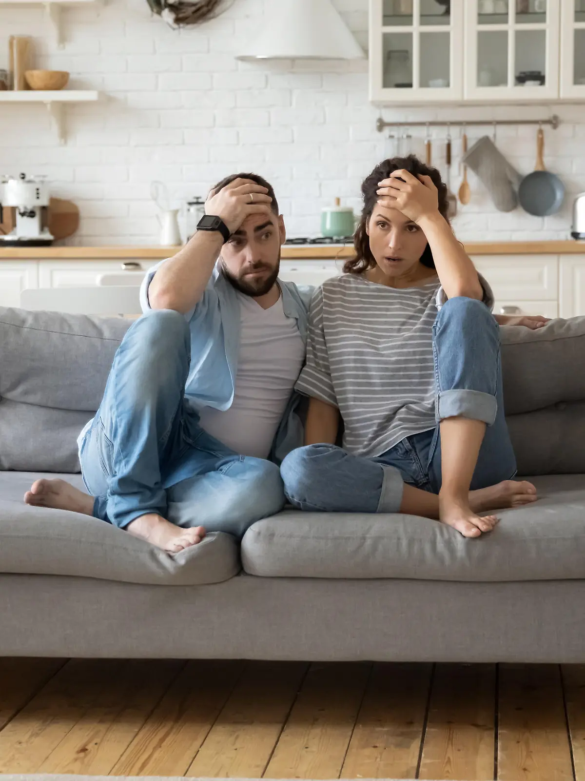 Tired mother and father sitting on couch feels annoyed exhausted while noisy little daughter and son shouting run around sofa where parents resting. Too active hyperactive kids, need repose concept