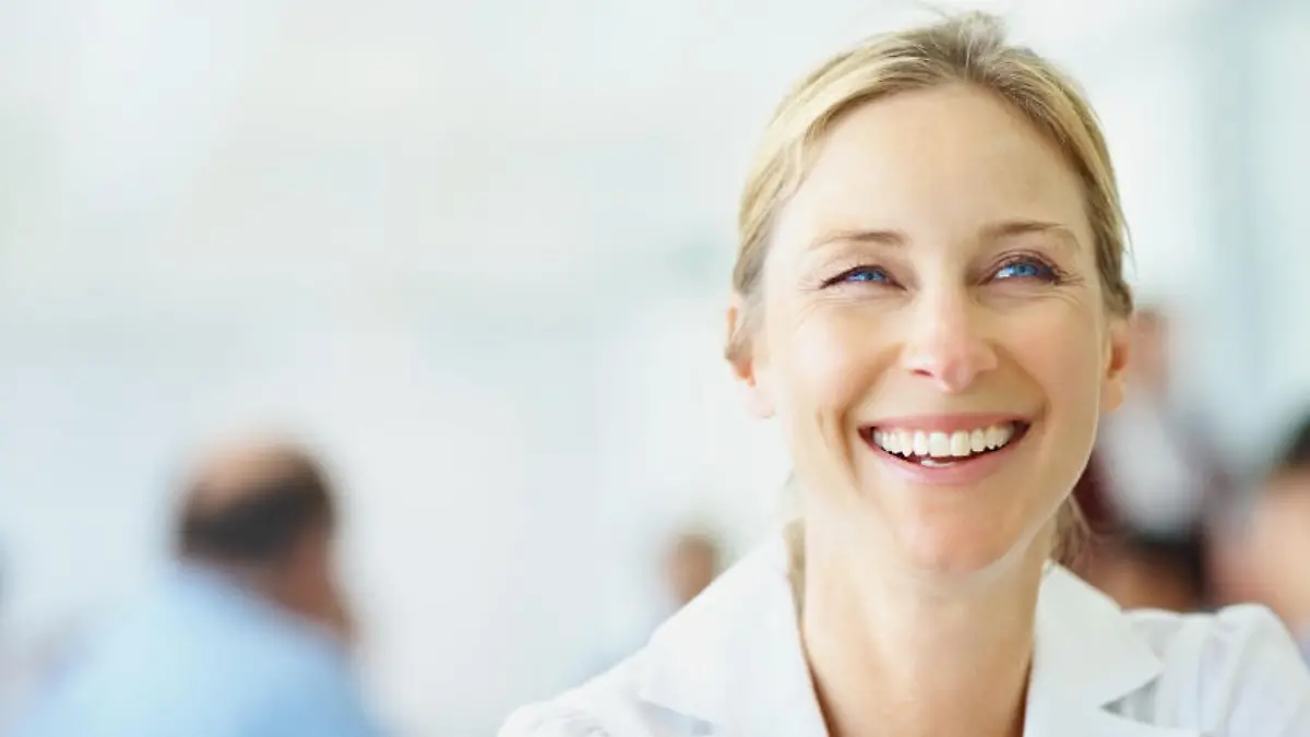 Closeup of a smiling business woman at the conference room with colleagues in background