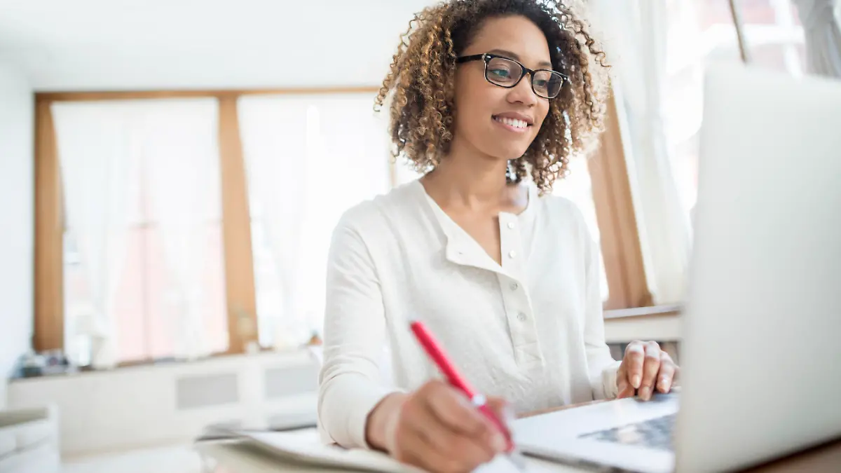 Young African American business woman working at home on a laptop computer and wearing glasses
