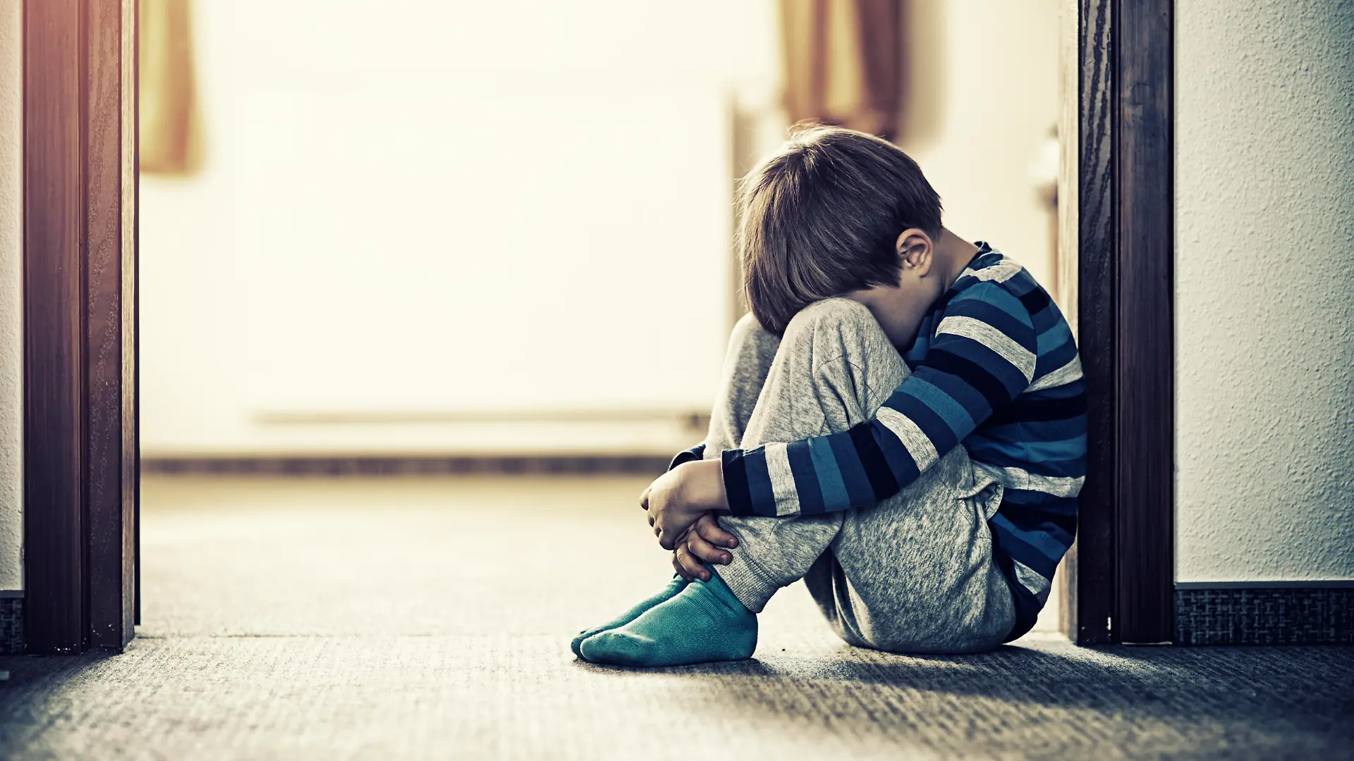 ein-deprimierter-kleine-junge-sitzt-auf-dem-boden