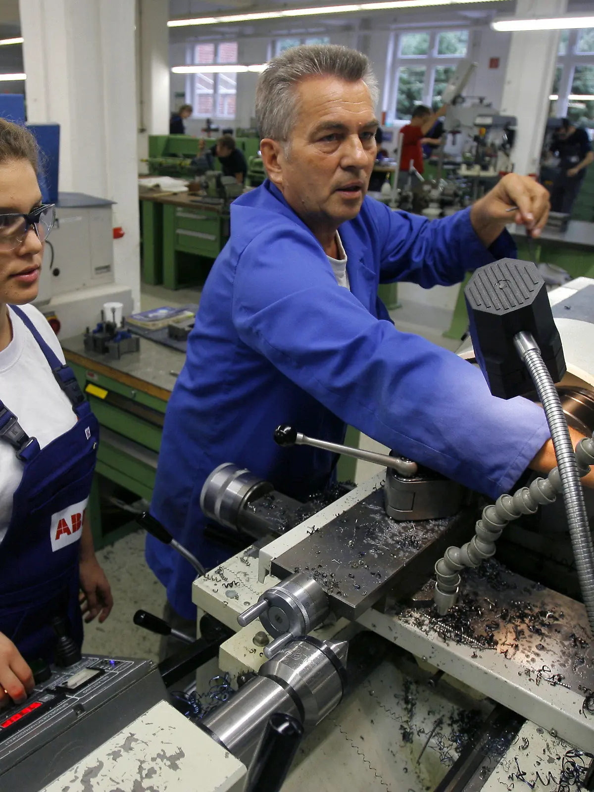 ARCHIV - Eine Auszubildende im Beruf der Zerspanungsmechanikerin, steht gemeinsam mit ihrem Meister an einer Drehbank im Ausbildungszentrum der Firma ABB in Berlin (Archivbild vom 23.09.2008). In wenigen Jahren werden
Millionen Fachkräfte fehlen. Entwarnung gibt es zwar nicht, doch laut einer Studie wird die Lücke nicht so groß wie befürchtet - auch weil es wirtschaftlich weniger steil bergauf geht als erhofft.  Foto: Tim Brakemeier/dpa  +++(c) dpa - Bildfunk+++