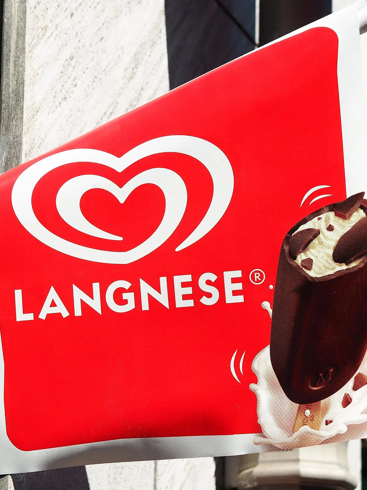 Ein Fahne mit dem Schriftzug und dem Logo von Langnese und einem Bild von einem Magnum-Eis hängt am 26.04.2016 in Berlin an einem Laden. Langnese gehört zur Unilever-Gruppe. Foto: Wolfram Steinberg/dpa