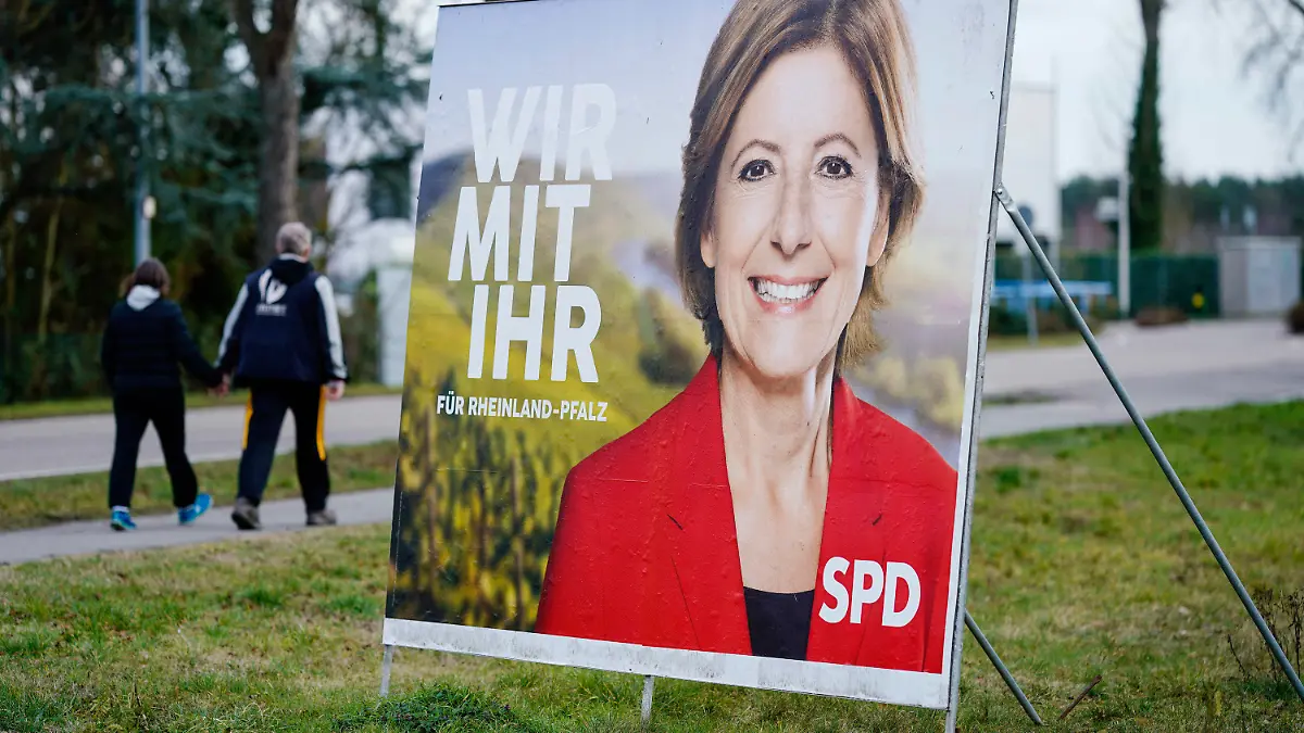 04.02.2021, Rheinland-Pfalz, Haßloch: Zwei Passanten gehen an einem Wahlplakat mit dem Konterfei von Malu Dreyer vorbei, der rheinland-pfälzischen Ministerpräsidentin und Spitzenkandidaten der SPD für die kommende Landtagswahl. (zu dpa: «Wie tickt Haßloch? - Vorwahlstimmung im Mini-Deutschland in der Pfalz») Foto: Uwe Anspach/dpa +++ dpa-Bildfunk +++