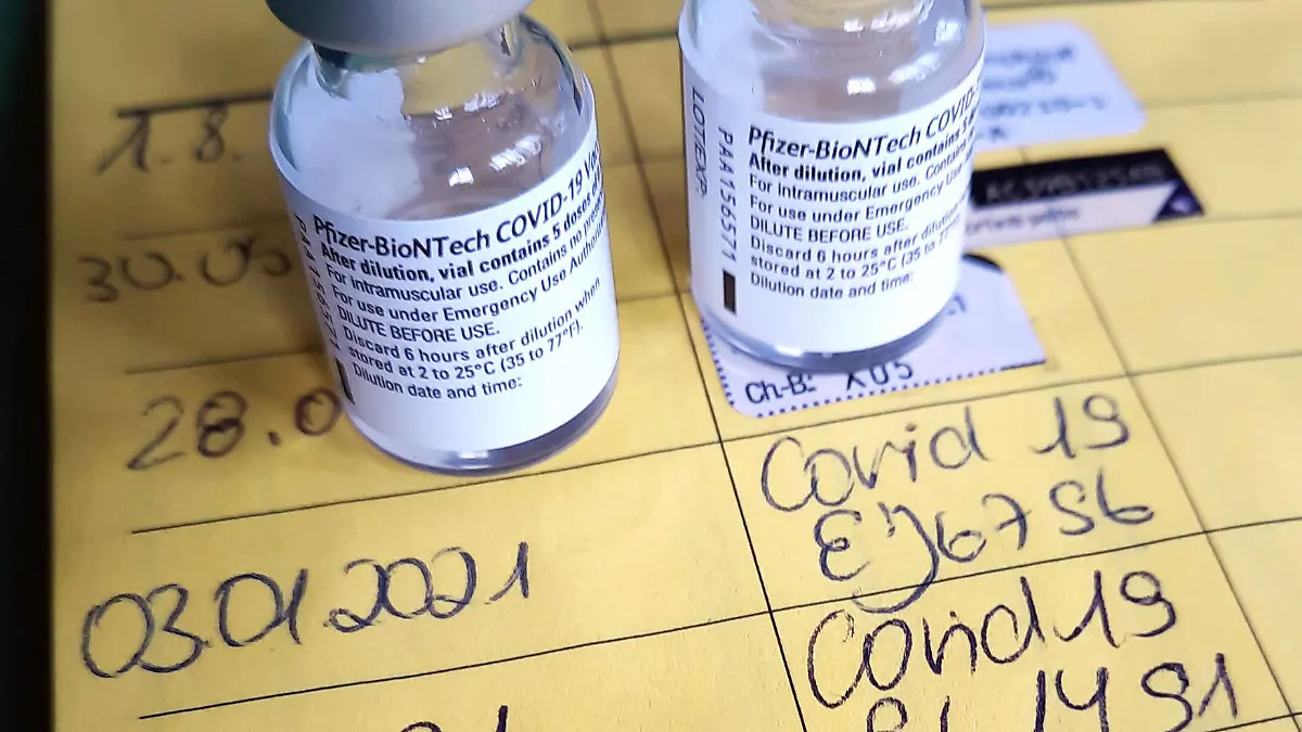 Symbolbild Corona-Impfung. Zwei Impfdosen, Impfspritze und der Eintrag der ersten und zweiten Corona-Impfung in einem Impfpass einer mit dem COVID-19-mRNA-Impfstoff der Firma BioNTech geimpften Person. Dortmund, 25.01.2021 *** Symbolic image Corona vaccination Two vaccine doses, vaccination syringe and the entry of the first and second Corona vaccination in a vaccination certificate of a person vaccinated with the COVID 19 mRNA vaccine from BioNTech Dortmund, 25 01 2021